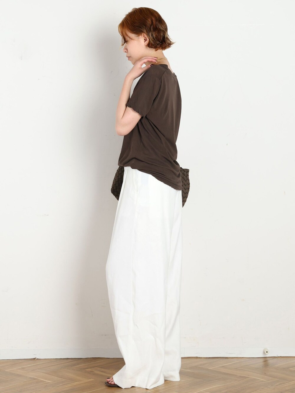 ホワイト系のスラックス、ブラウン系のTシャツ/カットソー、ブラウン系のクラッチバッグを着用したレディースの春コーディネートの2枚目の写真