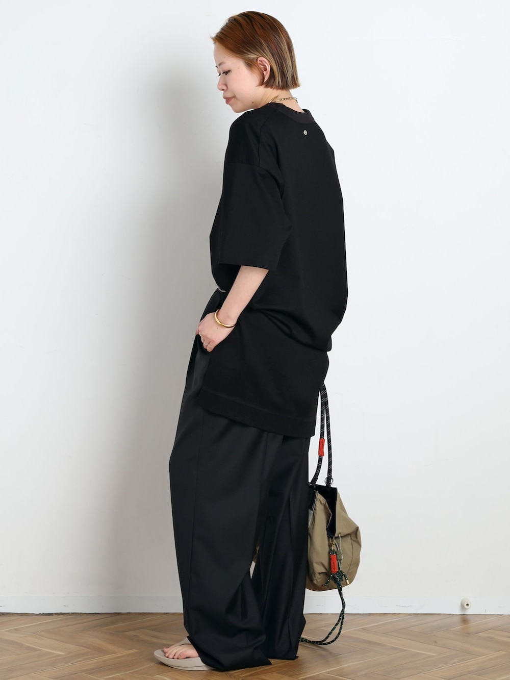 ブラック系のスラックス、ブラック系のTシャツ/カットソー、ベージュ系のサンダルを着用したレディースの春コーディネートの2枚目の写真