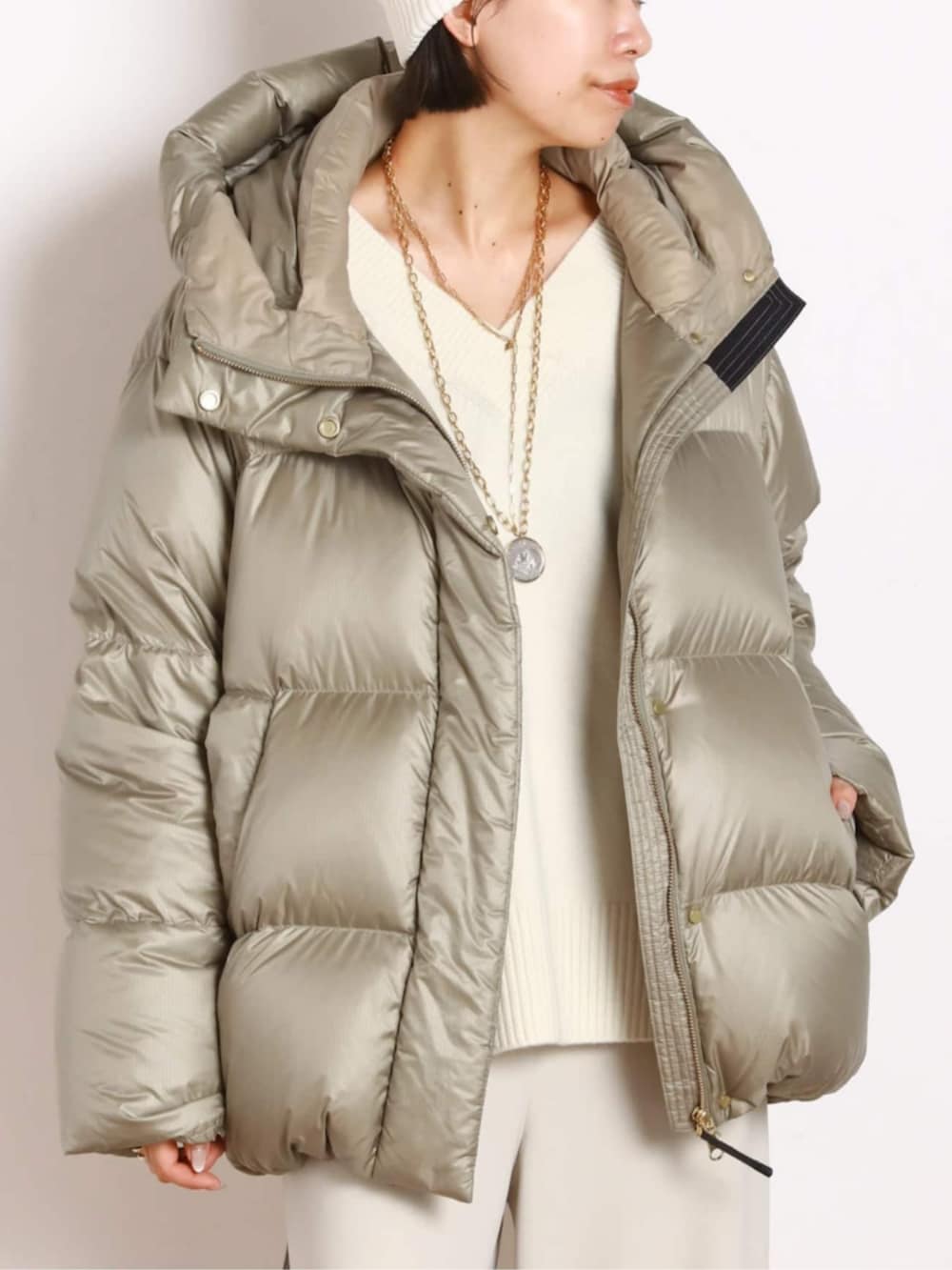 ベージュ系のダウンジャケット/コート、ホワイト系のスラックスを着用したレディースの秋コーディネートの4枚目の写真