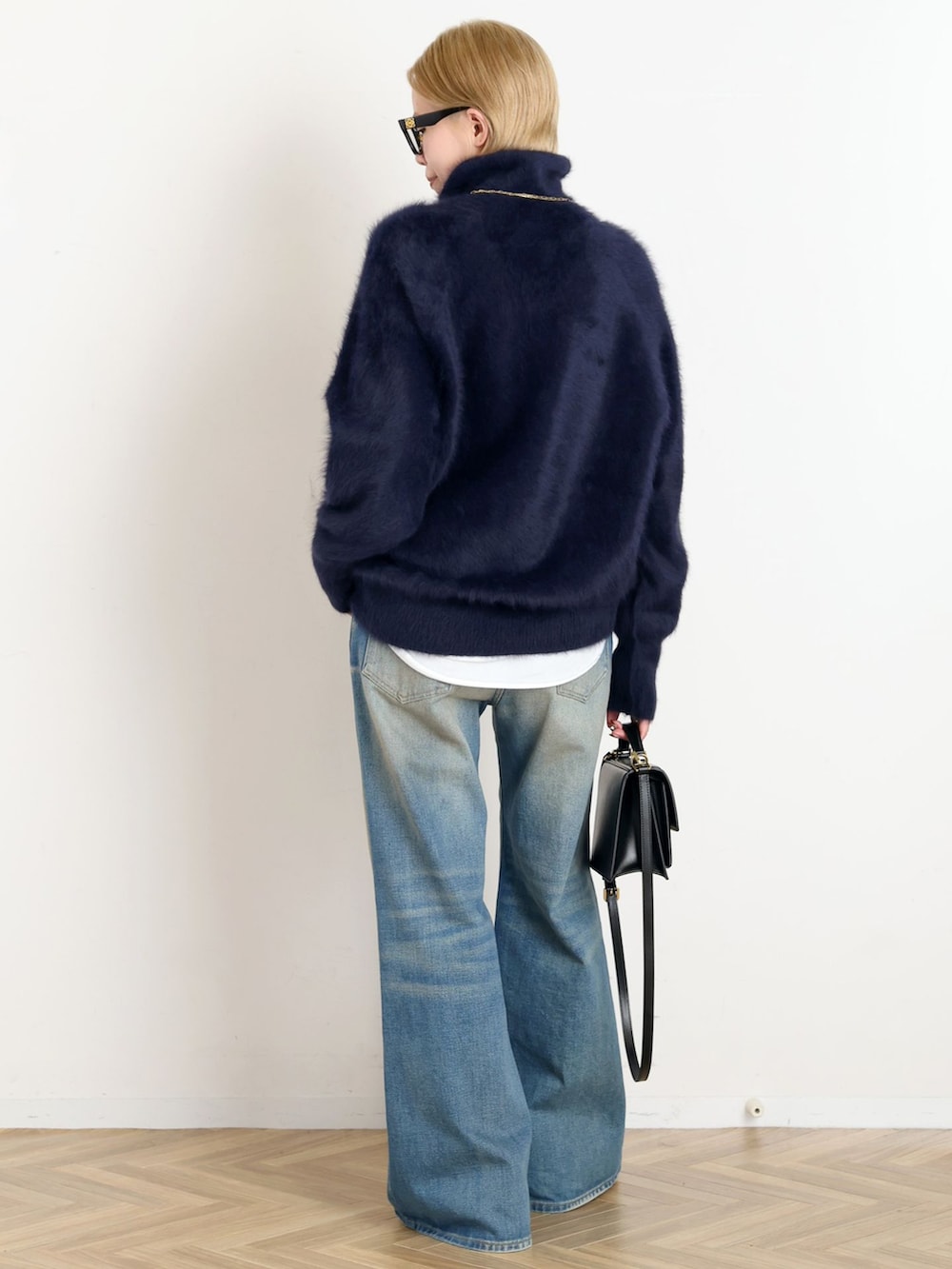 ブラック系のその他アウター、ブルー系のデニムパンツ、ブルー系のニット/セーターを着用したレディースの秋コーディネートの6枚目の写真