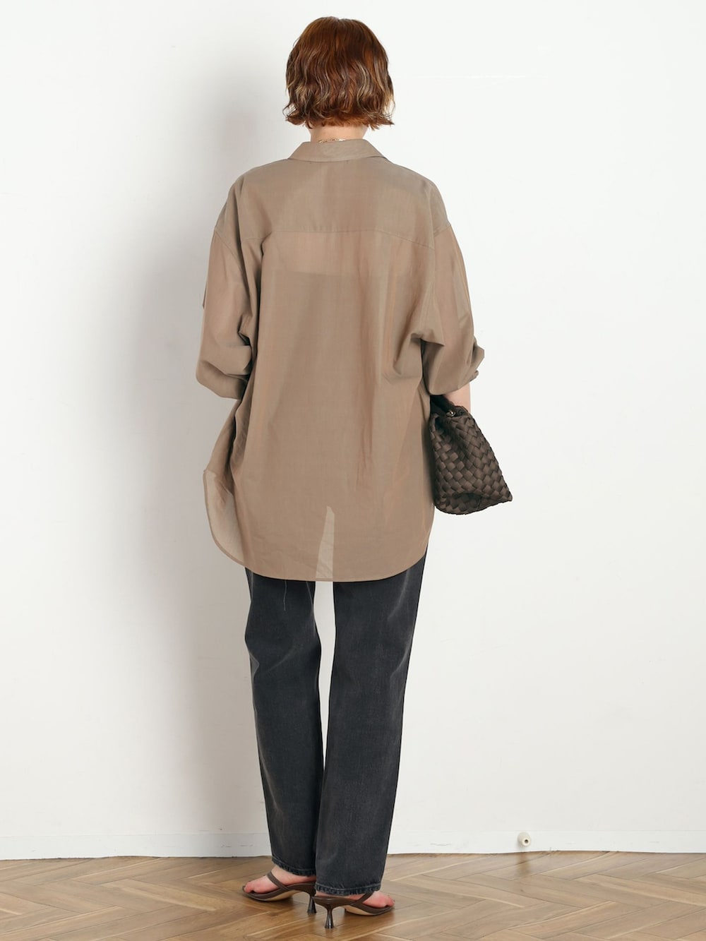ブラック系のデニムパンツ、ベージュ系のシャツ/ブラウス、ブラウン系のクラッチバッグを着用したレディースの春コーディネートの3枚目の写真
