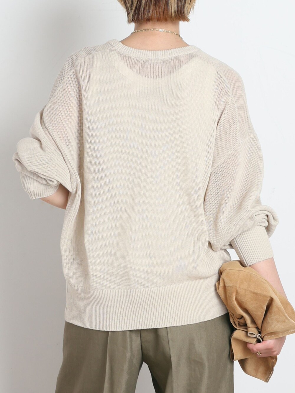 グリーン系のスラックス、ホワイト系のTシャツ/カットソー、ベージュ系のニット/セーターを着用したレディースの春コーディネートの6枚目の写真