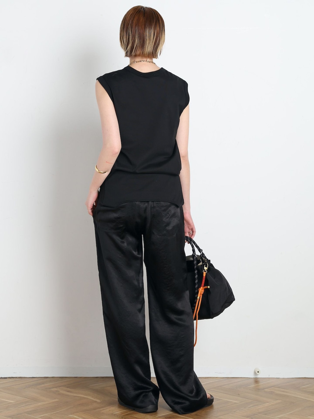 ブラック系のその他パンツ、ブラック系のTシャツ/カットソー、オレンジ系のその他小物を着用したレディースの春コーディネートの3枚目の写真