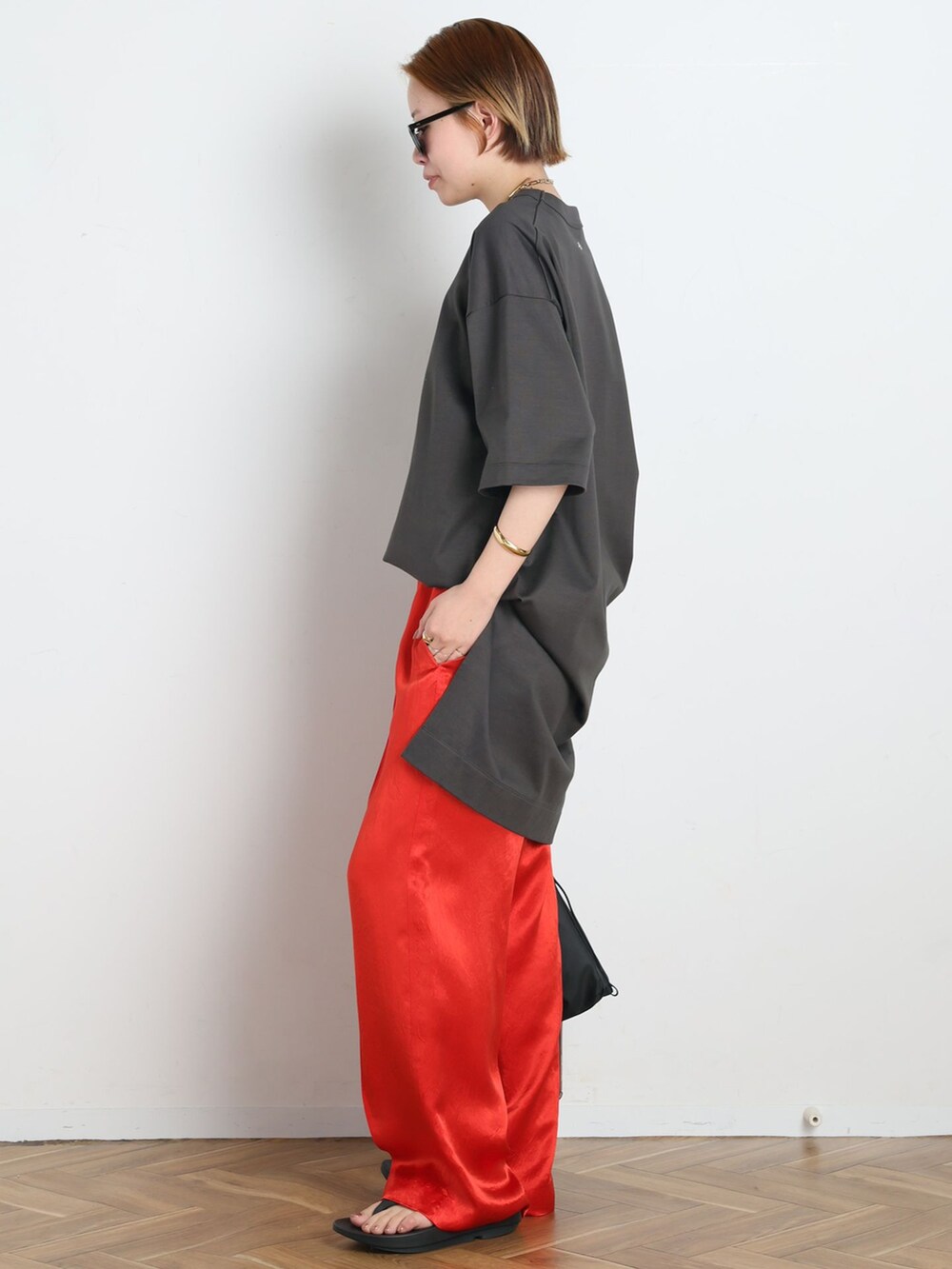 レッド系のその他パンツ、グレー系のTシャツ/カットソー、ブラック系のショルダーバッグを着用したレディースの春コーディネートの2枚目の写真