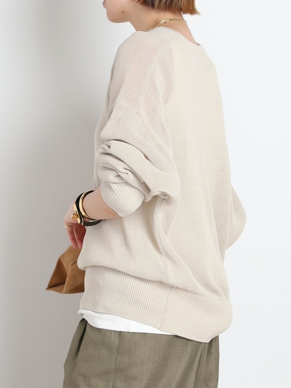 グリーン系のスラックス、ホワイト系のTシャツ/カットソー、ベージュ系のニット/セーターを着用したレディースの春コーディネートの5枚目の写真