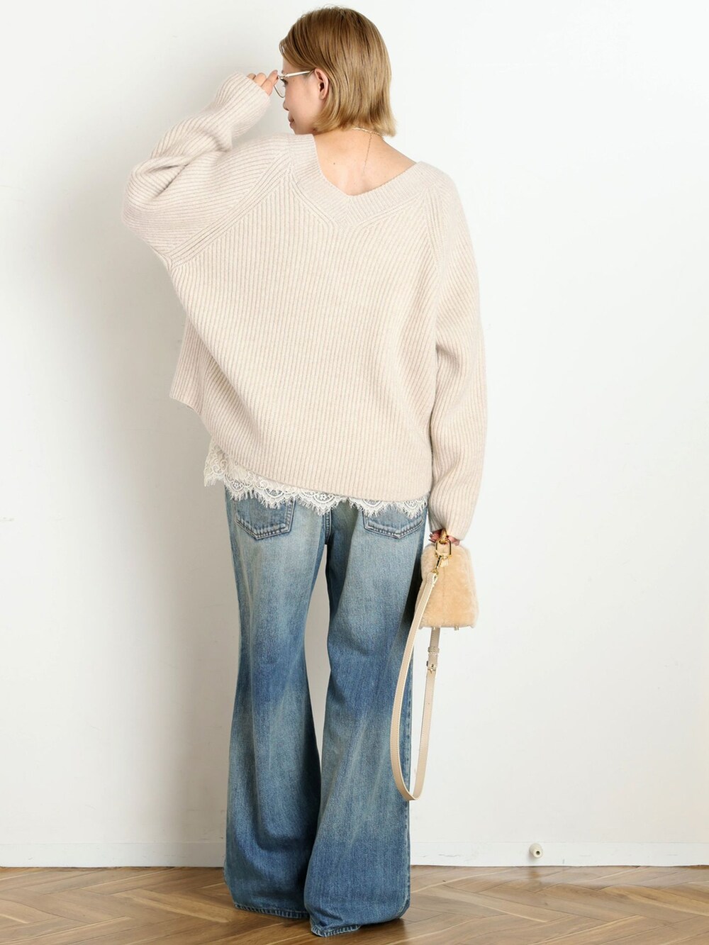 ブルー系のデニムパンツ、ホワイト系のニット/セーター、ベージュ系のパンプスを着用したレディースの秋コーディネートの3枚目の写真