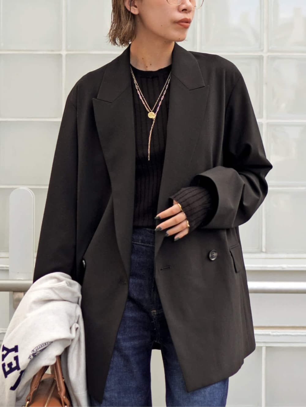 ブラウン系のテーラードジャケット、ブラウン系のニット/セーター、イエロー系のハンドバッグを着用したレディースの秋コーディネートの5枚目の写真