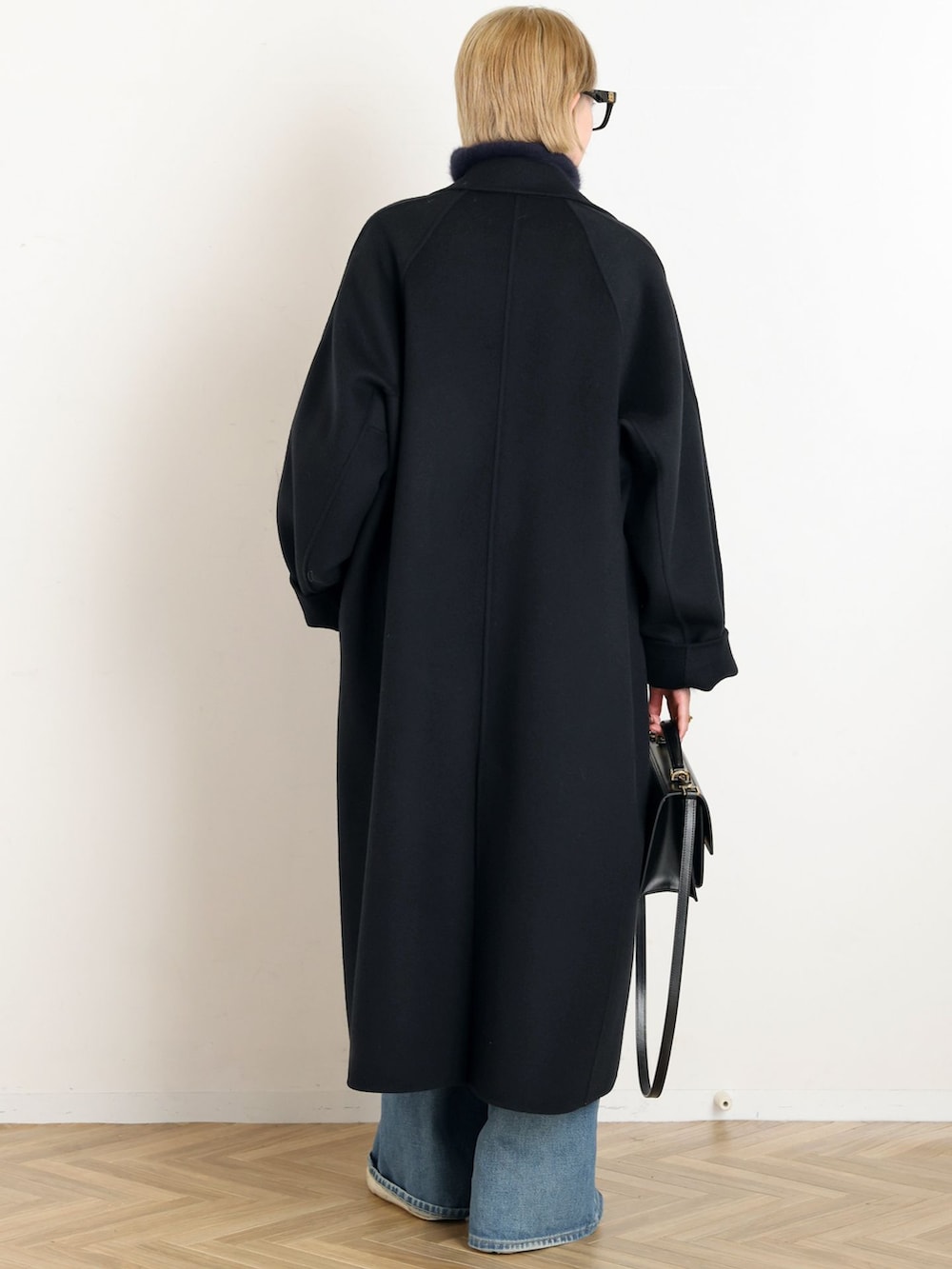 ブラック系のその他アウター、ブルー系のデニムパンツ、ブルー系のニット/セーターを着用したレディースの秋コーディネートの3枚目の写真