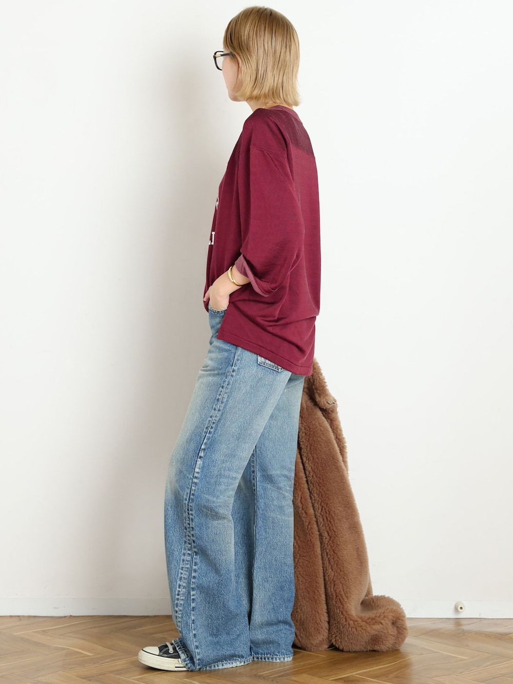 ブルー系のデニムパンツ、レッド系のTシャツ/カットソー、ゴールド系のブレスレットを着用したレディースの秋コーディネートの2枚目の写真
