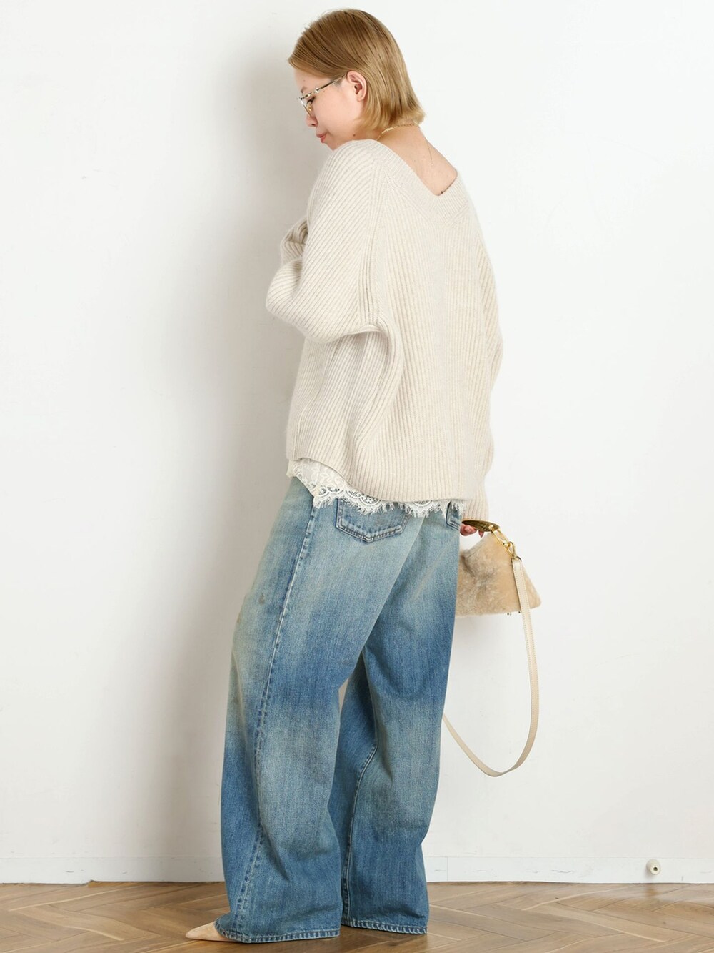 ブルー系のデニムパンツ、ホワイト系のニット/セーター、ベージュ系のパンプスを着用したレディースの秋コーディネートの2枚目の写真