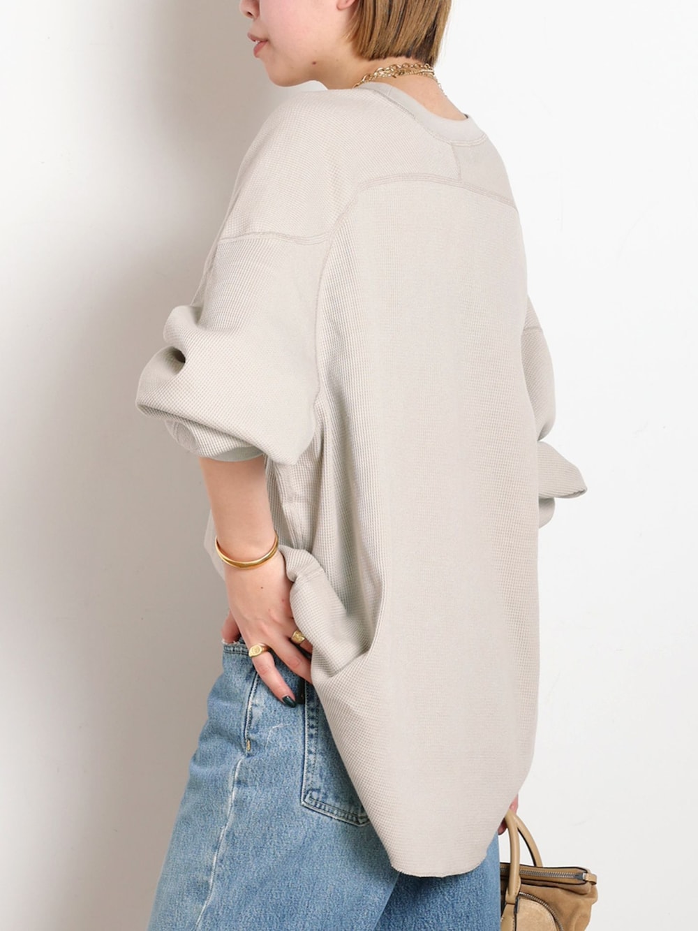 ブルー系のデニムパンツ、ベージュ系のTシャツ/カットソー、ゴールド系のサンダルを着用したレディースの冬コーディネートの5枚目の写真