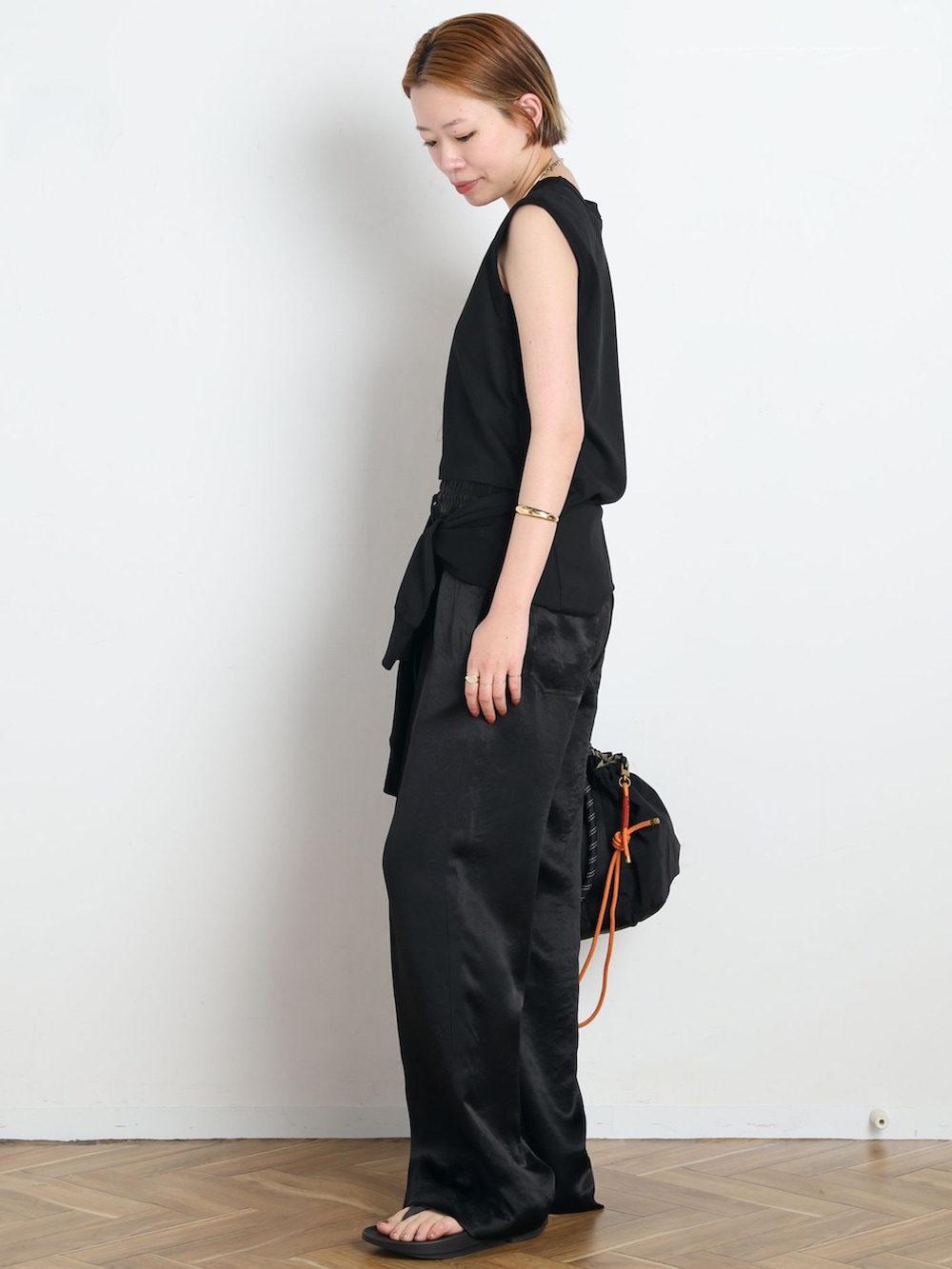 ブラック系のその他パンツ、ブラック系のTシャツ/カットソー、オレンジ系のその他小物を着用したレディースの春コーディネートの2枚目の写真