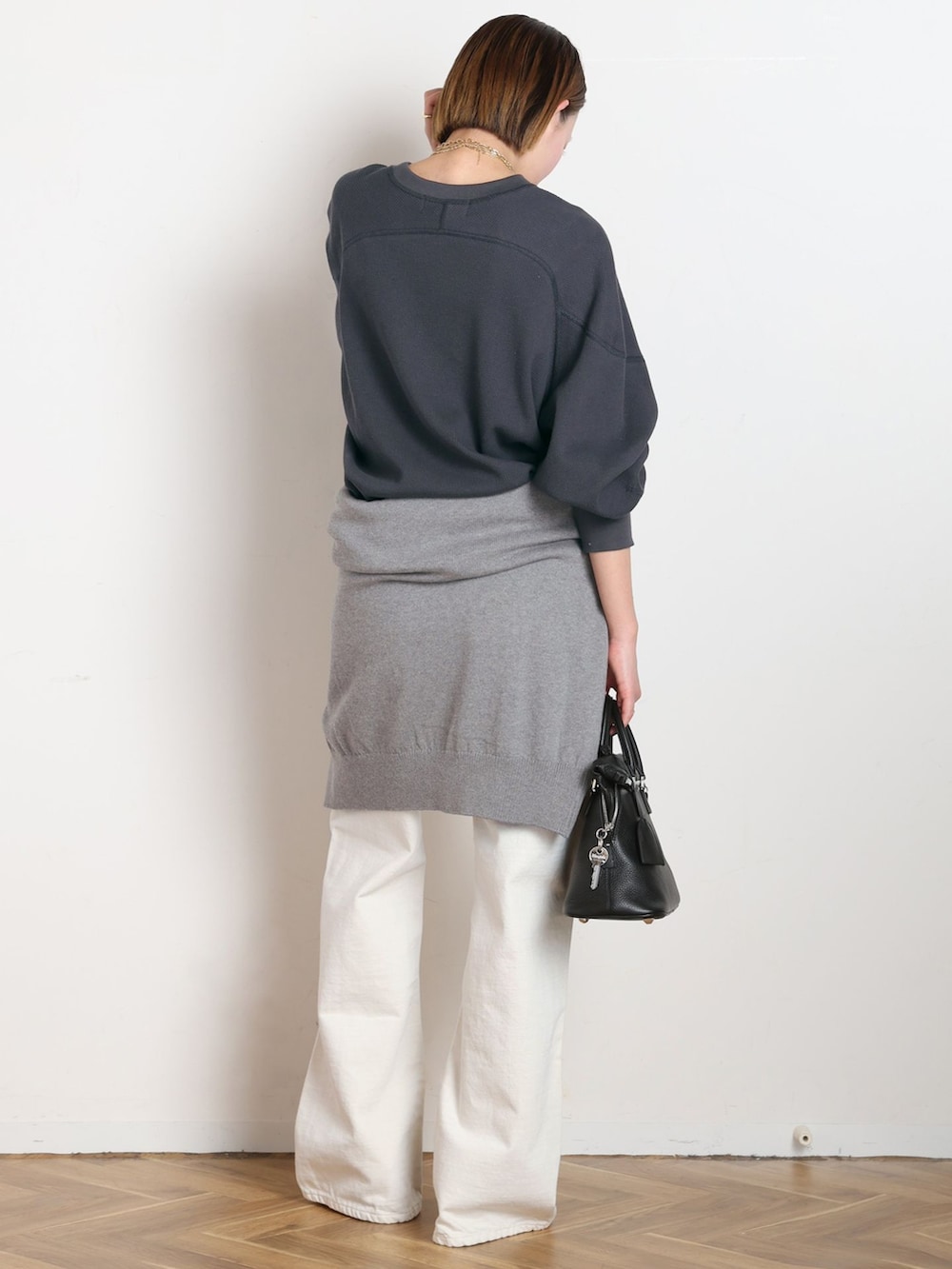 ホワイト系のデニムパンツ、ブラック系のTシャツ/カットソー、グレー系のニット/セーターを着用したレディースの冬コーディネートの3枚目の写真