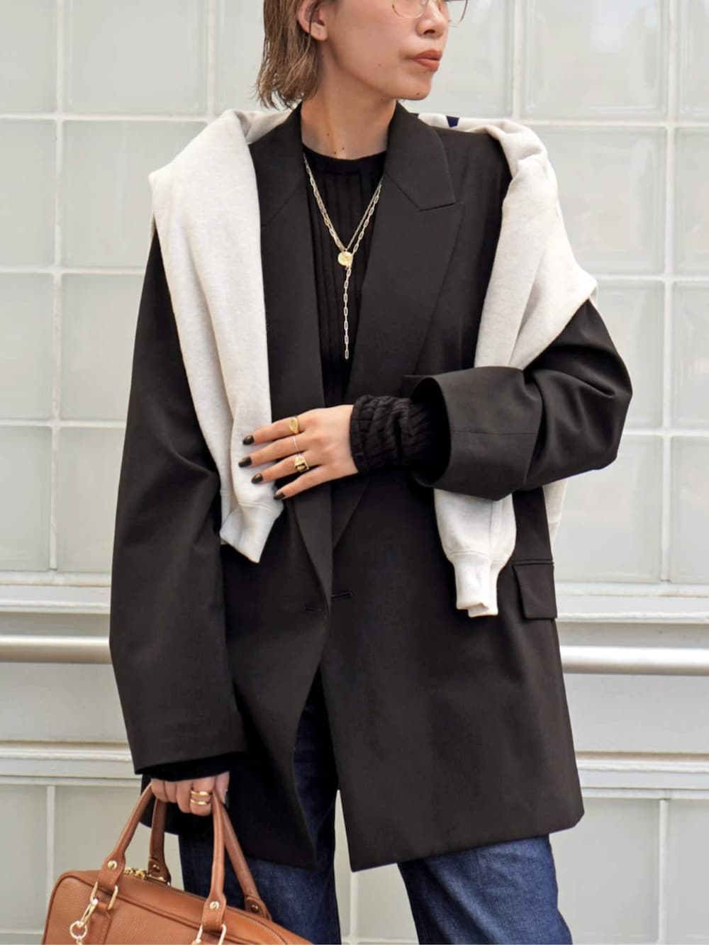 ブラウン系のテーラードジャケット、ブラウン系のニット/セーター、イエロー系のハンドバッグを着用したレディースの秋コーディネートの4枚目の写真