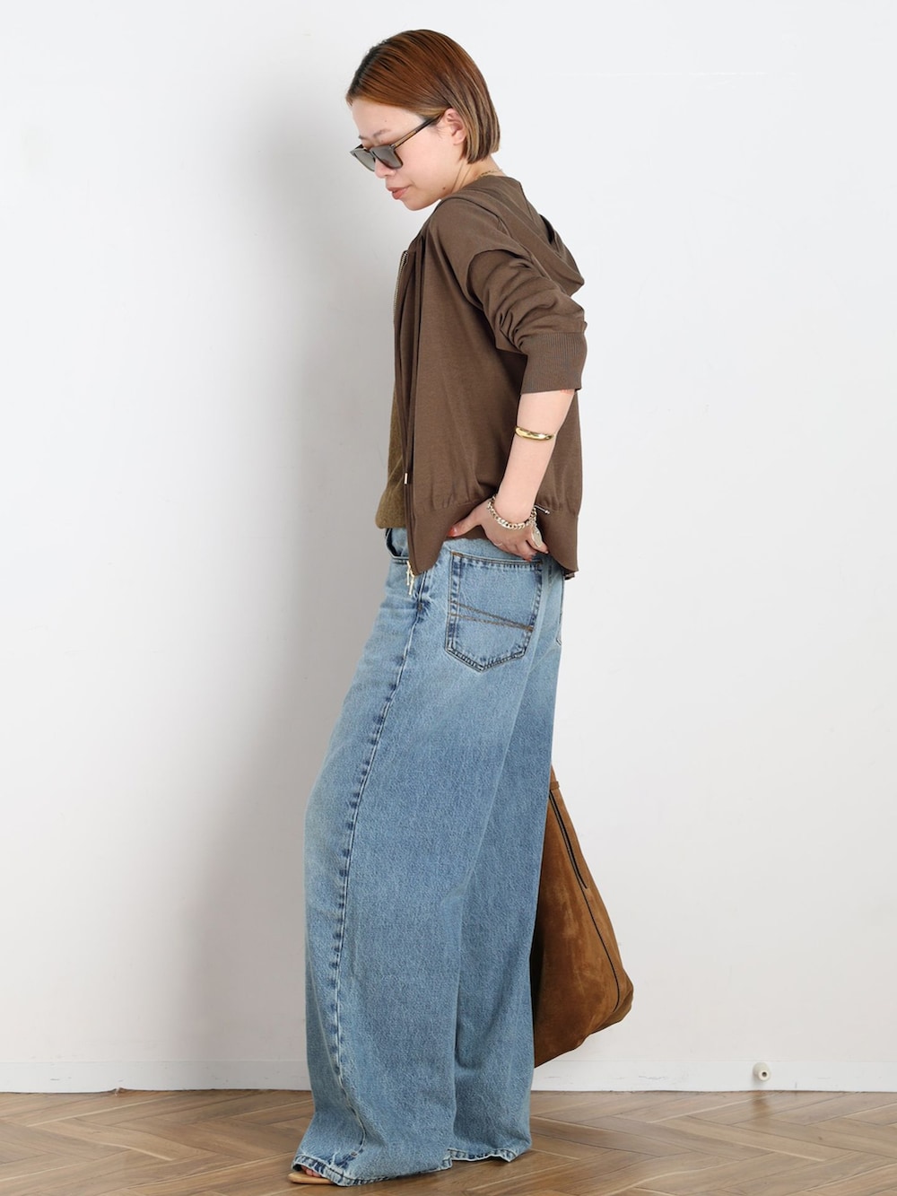 ブルー系のデニムパンツ、ブラウン系のパーカー、イエロー系のニット/セーターを着用したレディースの春コーディネートの2枚目の写真