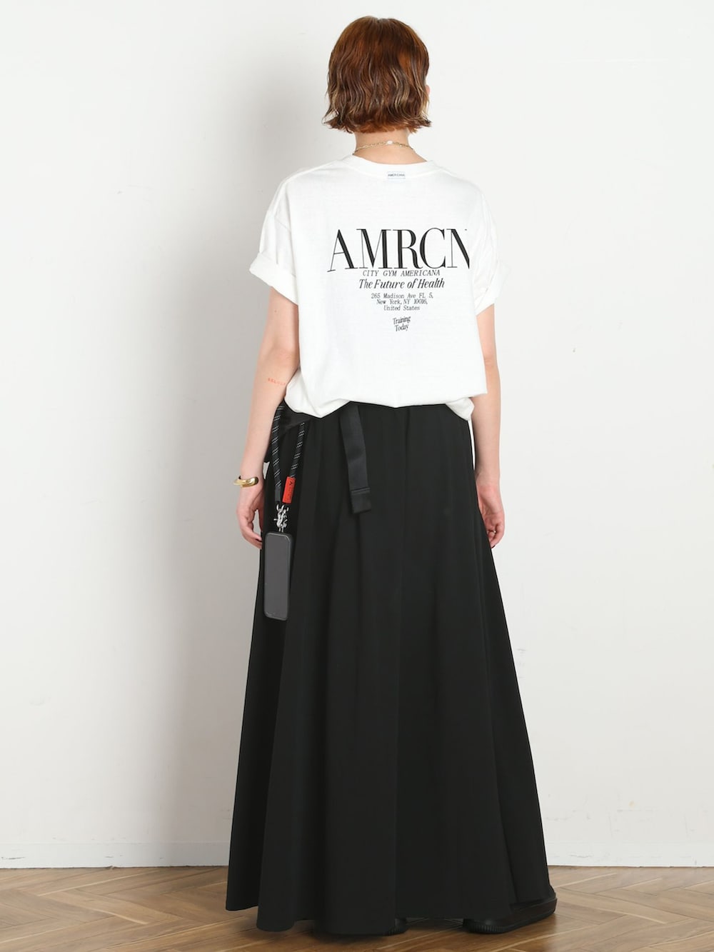 ブラック系のスカート、ホワイト系のTシャツ/カットソー、ブラック系のサンダルを着用したレディースの春コーディネートの3枚目の写真