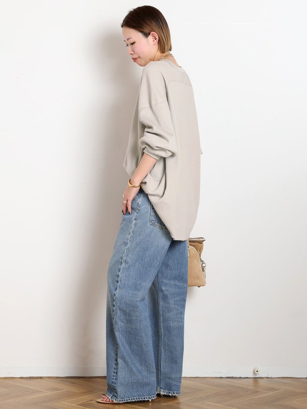 ブルー系のデニムパンツ、ベージュ系のTシャツ/カットソー、ゴールド系のサンダルを着用したレディースの冬コーディネートの2枚目の写真