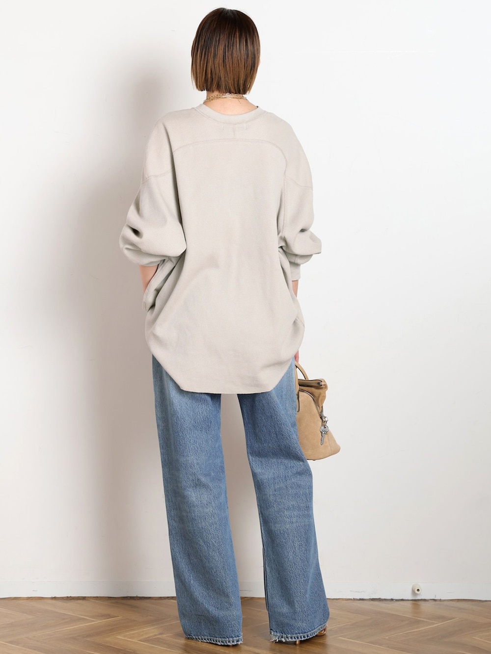 ブルー系のデニムパンツ、ベージュ系のTシャツ/カットソー、ゴールド系のサンダルを着用したレディースの冬コーディネートの3枚目の写真