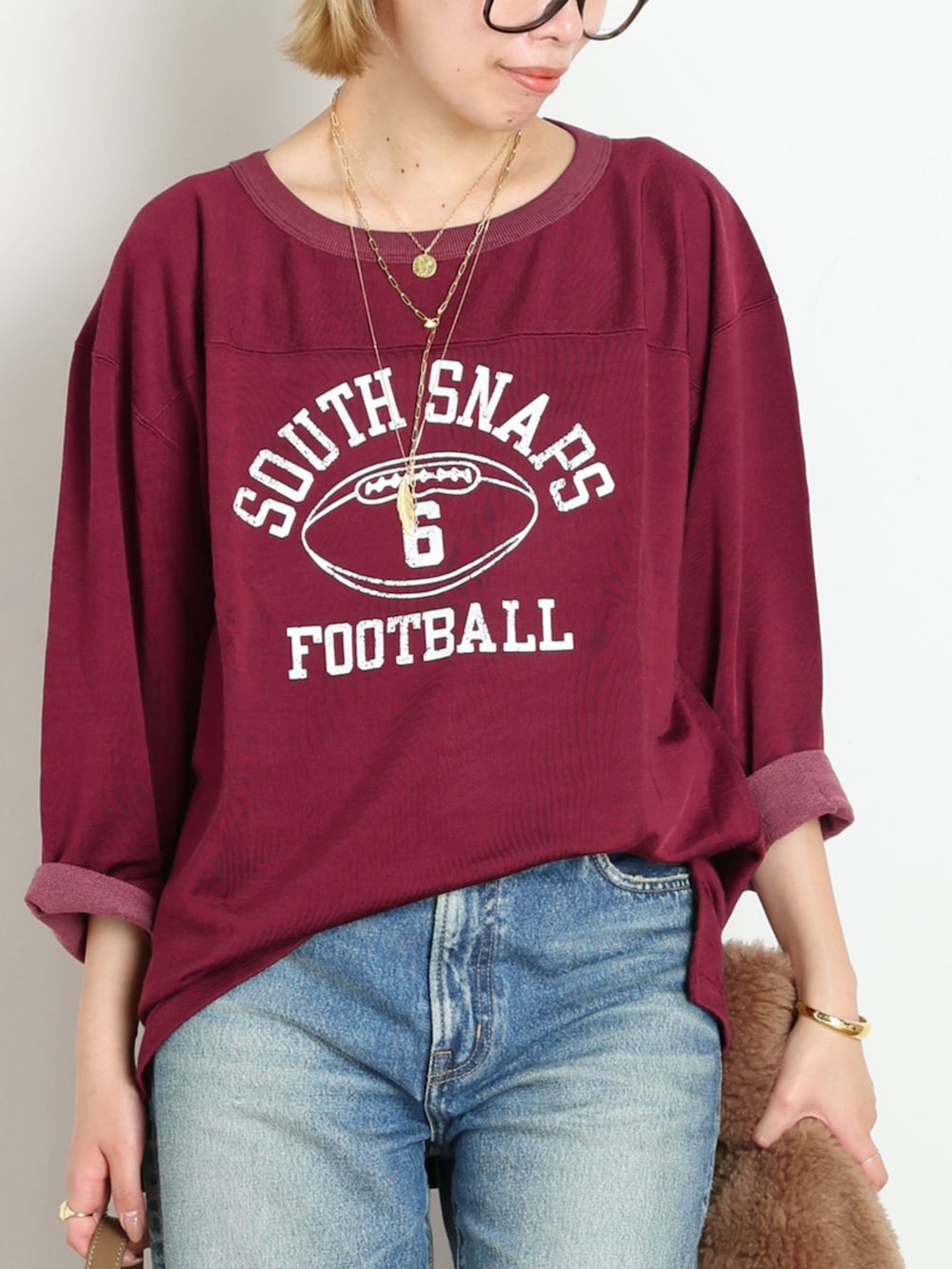 ブルー系のデニムパンツ、レッド系のTシャツ/カットソー、ゴールド系のブレスレットを着用したレディースの秋コーディネートの4枚目の写真