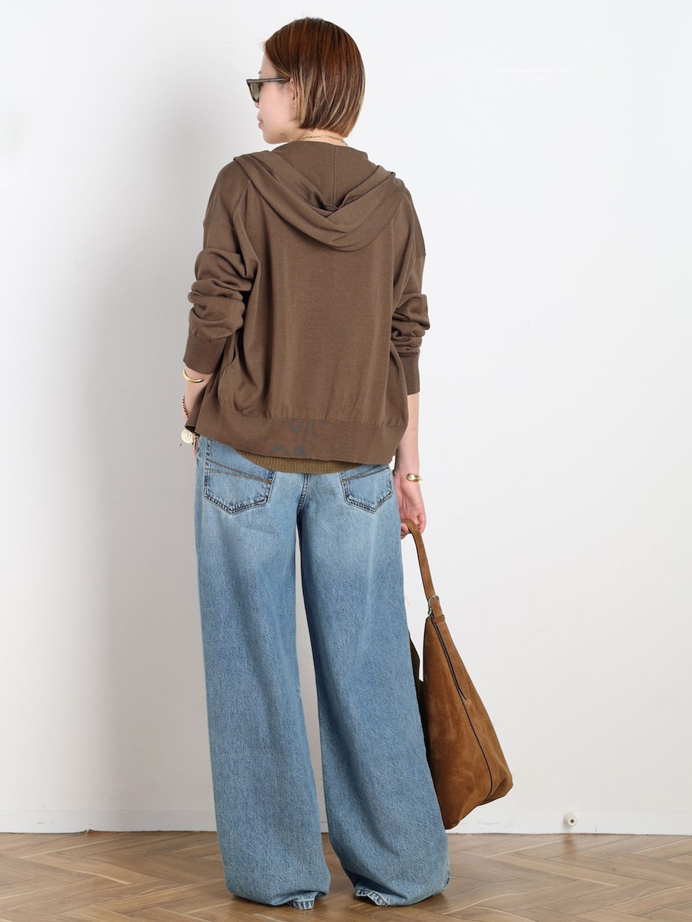 ブルー系のデニムパンツ、ブラウン系のパーカー、イエロー系のニット/セーターを着用したレディースの春コーディネートの3枚目の写真