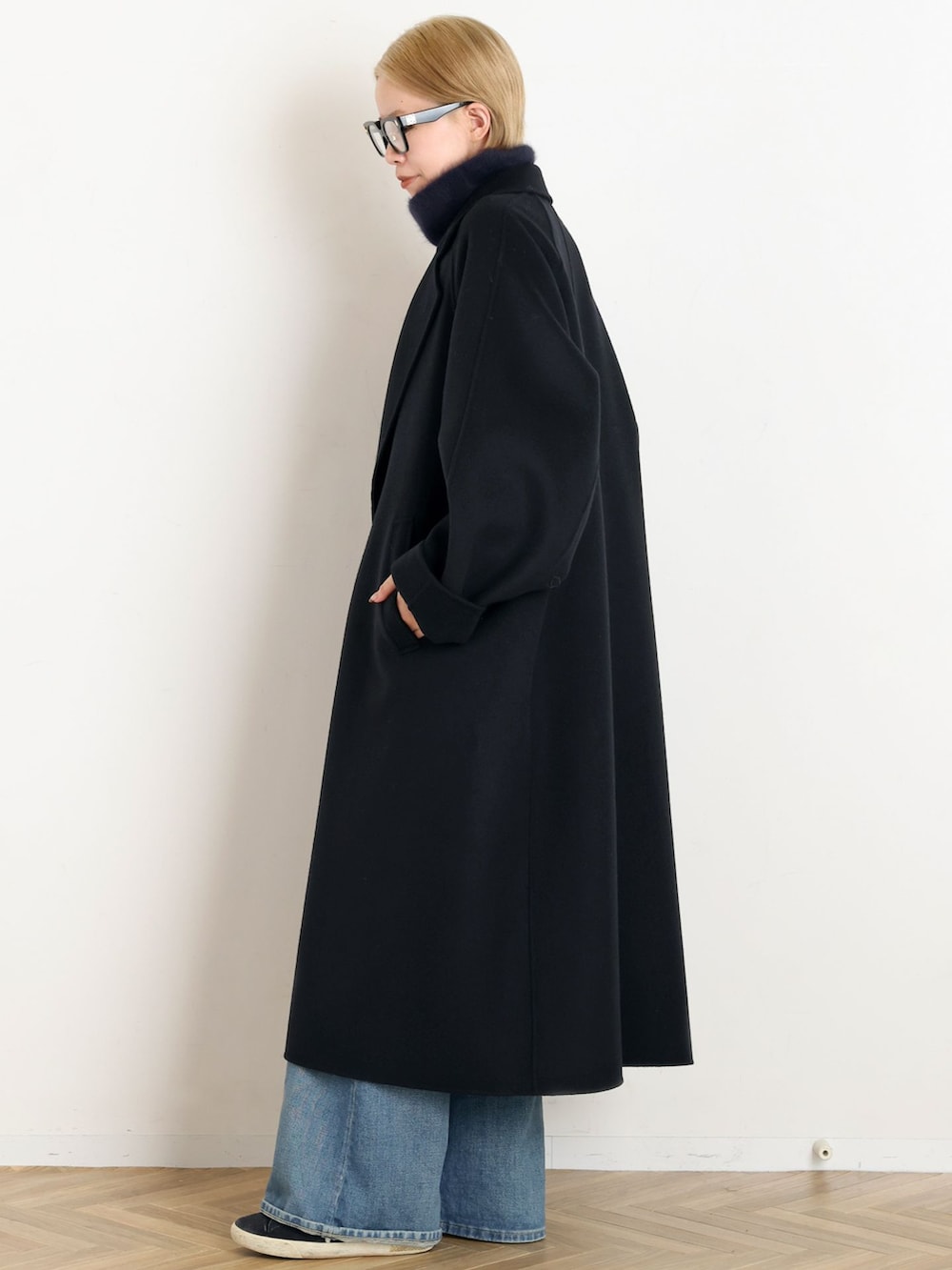 ブラック系のその他アウター、ブルー系のデニムパンツ、ブルー系のニット/セーターを着用したレディースの秋コーディネートの2枚目の写真