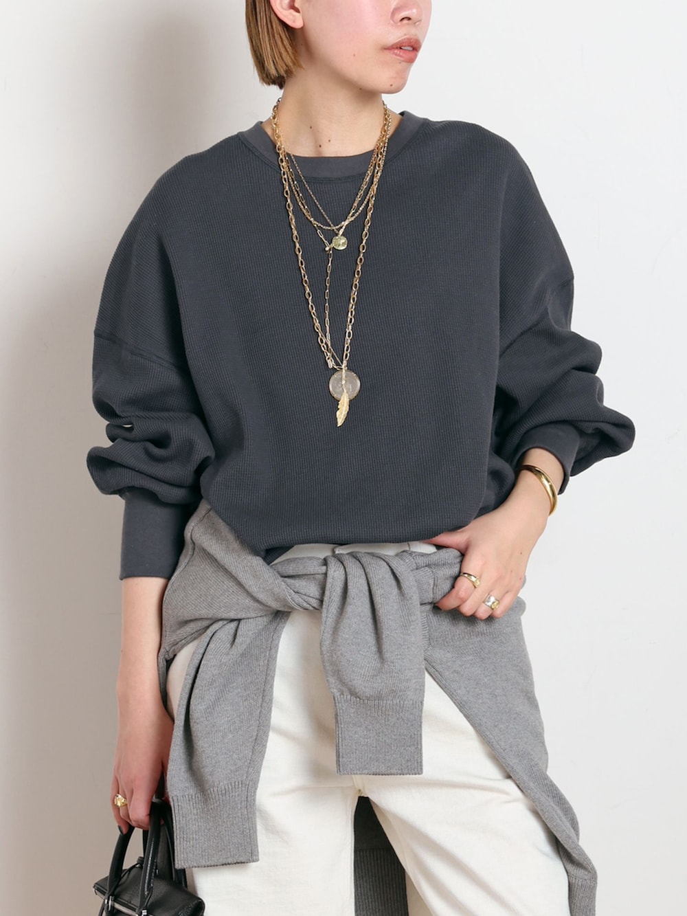 ホワイト系のデニムパンツ、ブラック系のTシャツ/カットソー、グレー系のニット/セーターを着用したレディースの冬コーディネートの4枚目の写真