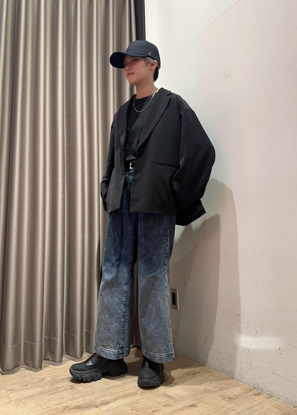 ブルー系のデニムパンツ、ブラック系のテーラードジャケット、ブラック系のキャップを着用したメンズの春コーディネートの2枚目の写真