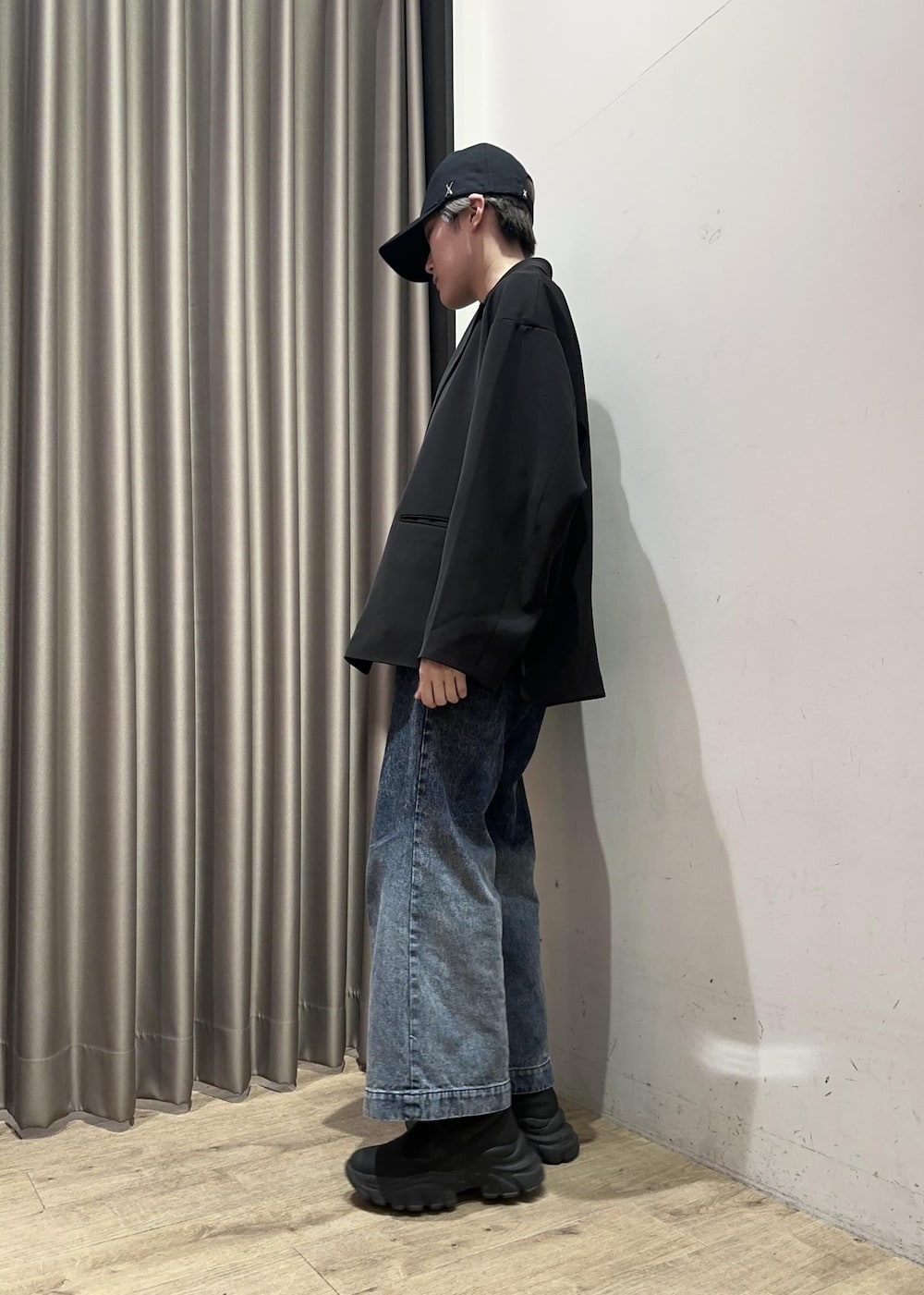 ブルー系のデニムパンツ、ブラック系のテーラードジャケット、ブラック系のキャップを着用したメンズの春コーディネートの3枚目の写真