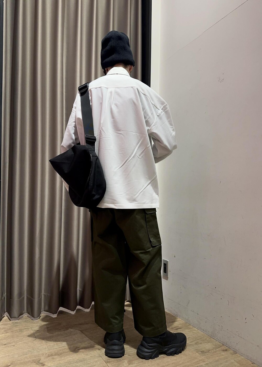 グリーン系のカーゴパンツ、ブラック系のメッセンジャーバッグ、ホワイト系のシャツ/ブラウスを着用したメンズの冬コーディネートの3枚目の写真