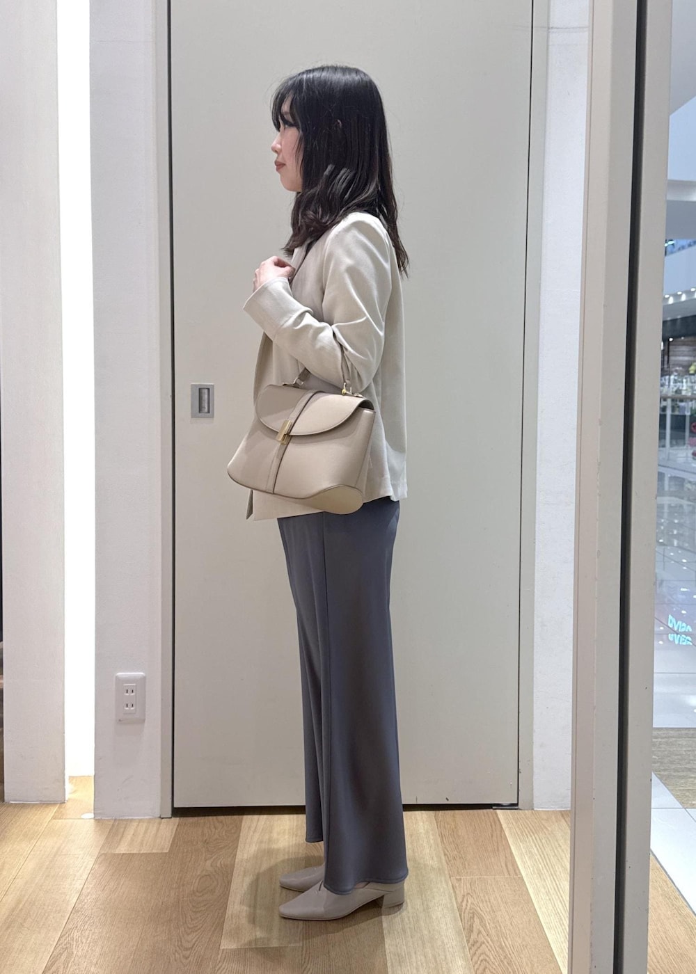 ベージュ系のパンプス、ベージュ系のショルダーバッグ、ブルー系のスカートを着用したレディースの春コーディネートの2枚目の写真