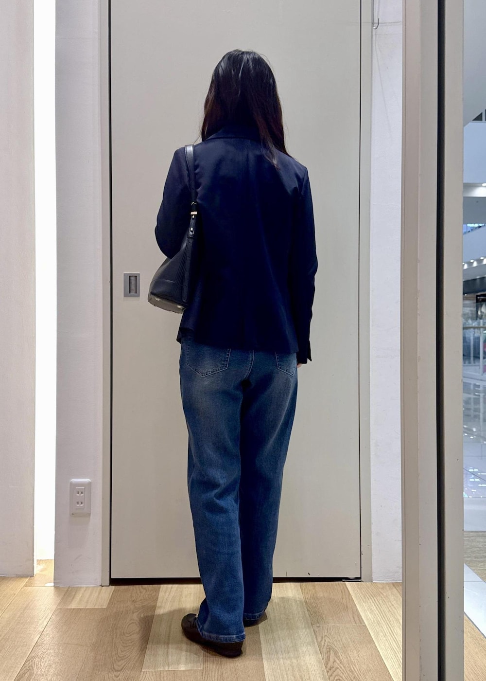 ブラック系のショルダーバッグ、ブラック系のローファー、ブルー系のテーラードジャケットを着用したレディースの冬コーディネートの3枚目の写真