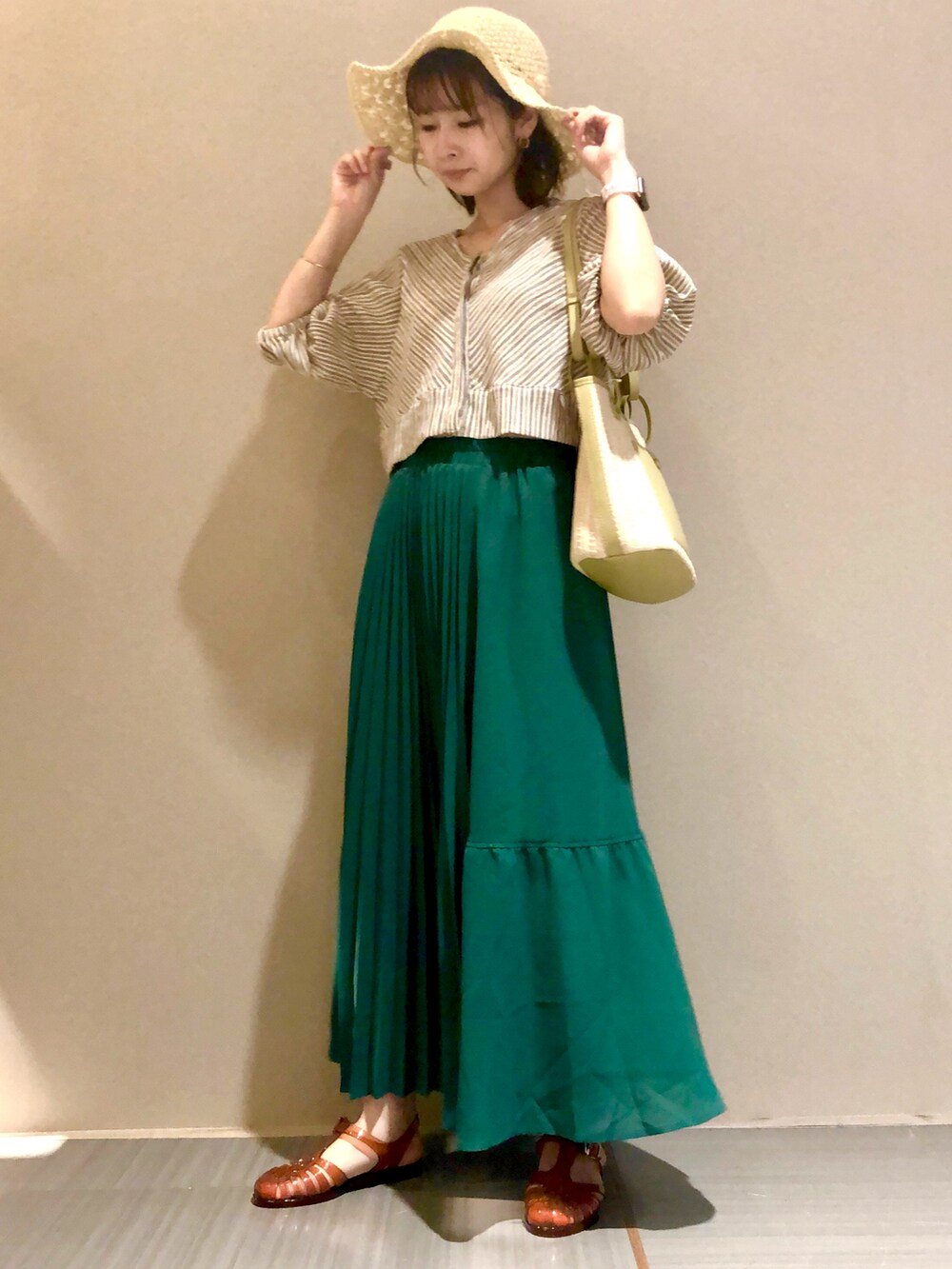 グリーン系のトートバッグ、グリーン系のスカート、ベージュ系のシャツ/ブラウスを着用したレディースの夏コーディネートの2枚目の写真