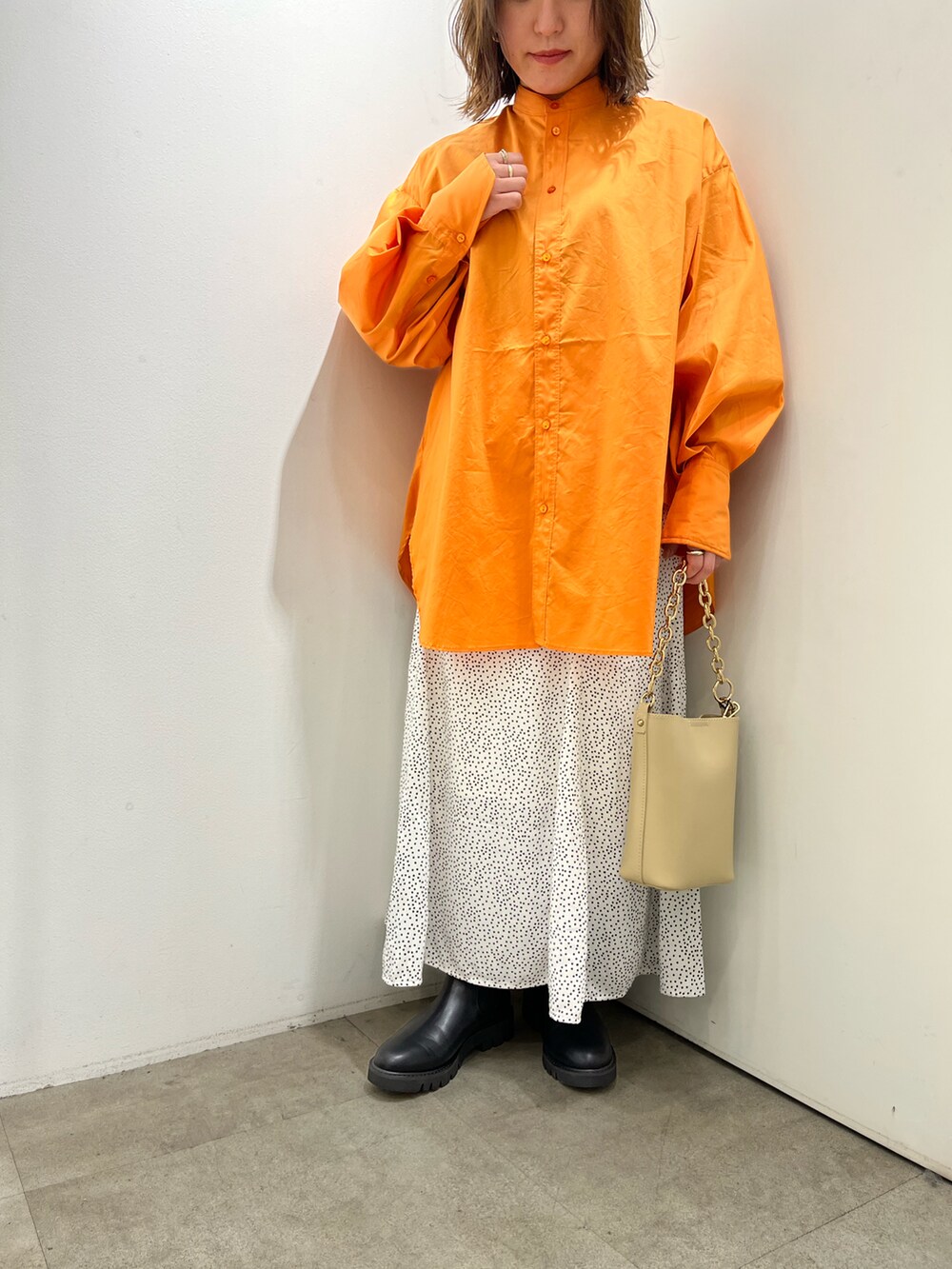 ベージュ系のショルダーバッグ、オレンジ系のシャツ/ブラウス、ホワイト系のスカートを着用したレディースの春コーディネートの3枚目の写真