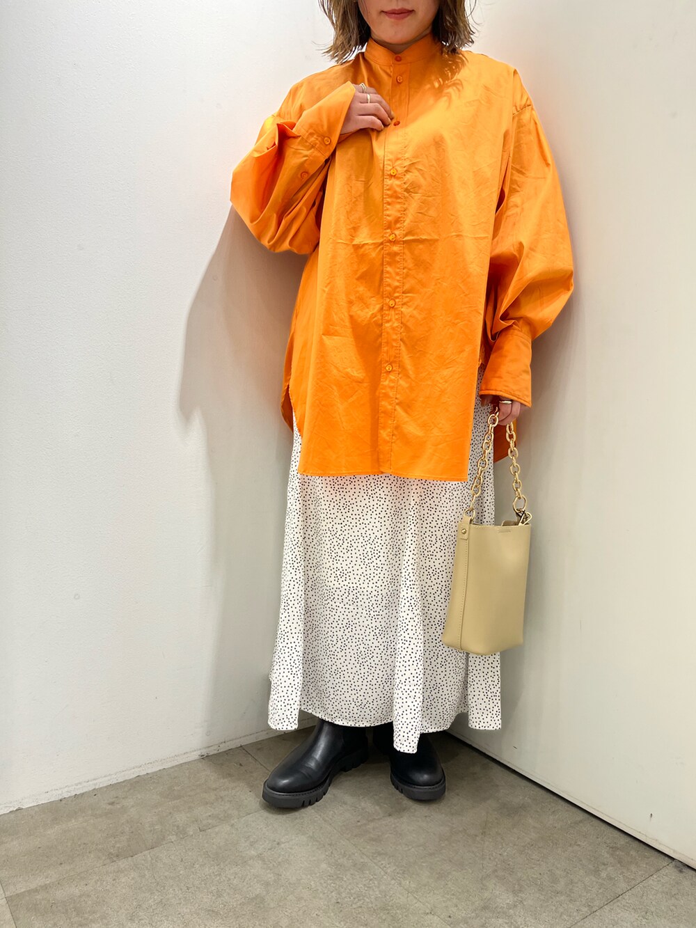 ベージュ系のショルダーバッグ、オレンジ系のシャツ/ブラウス、ホワイト系のスカートを着用したレディースの春コーディネートの2枚目の写真