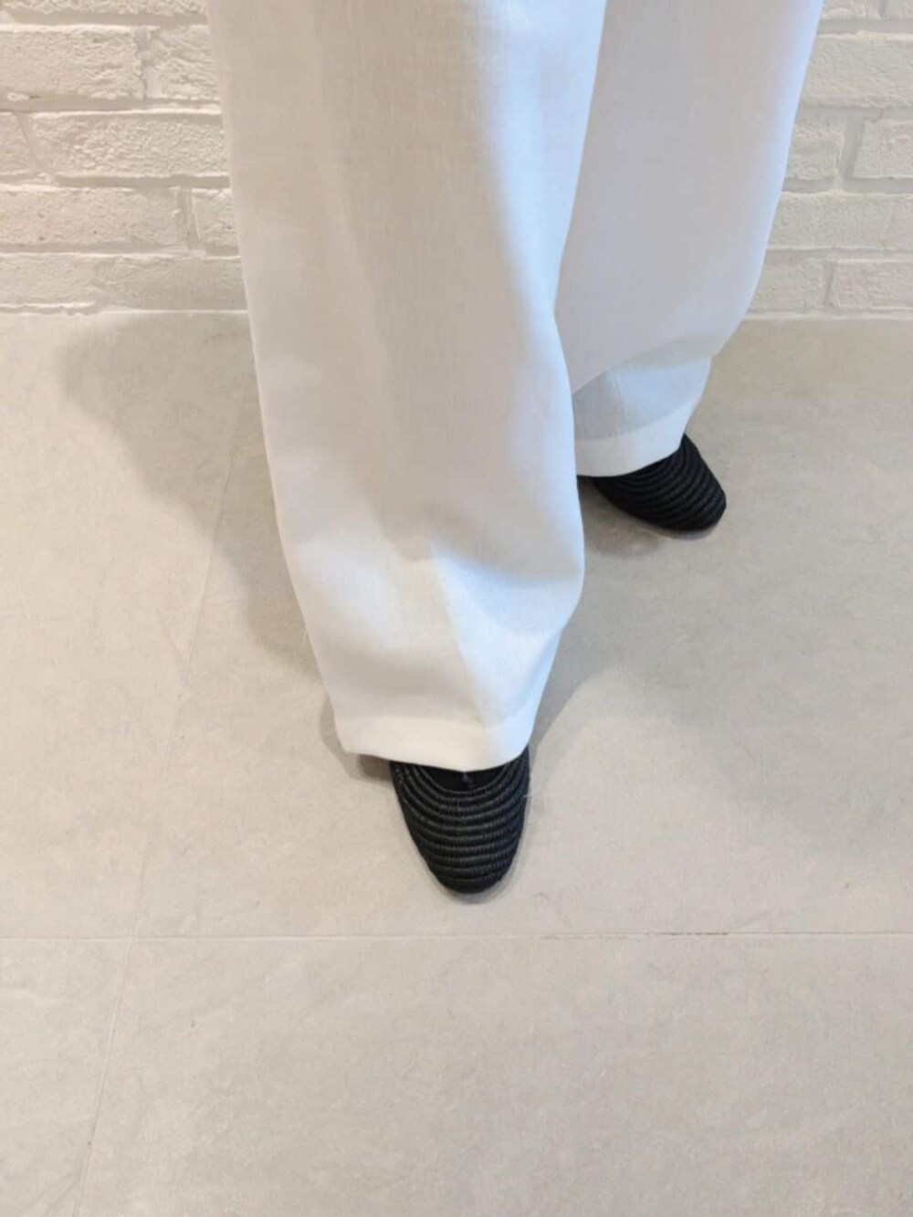 ホワイト系のノーカラージャケット、ブルー系のタンクトップ、ホワイト系のその他パンツを着用したレディースの夏コーディネートの6枚目の写真