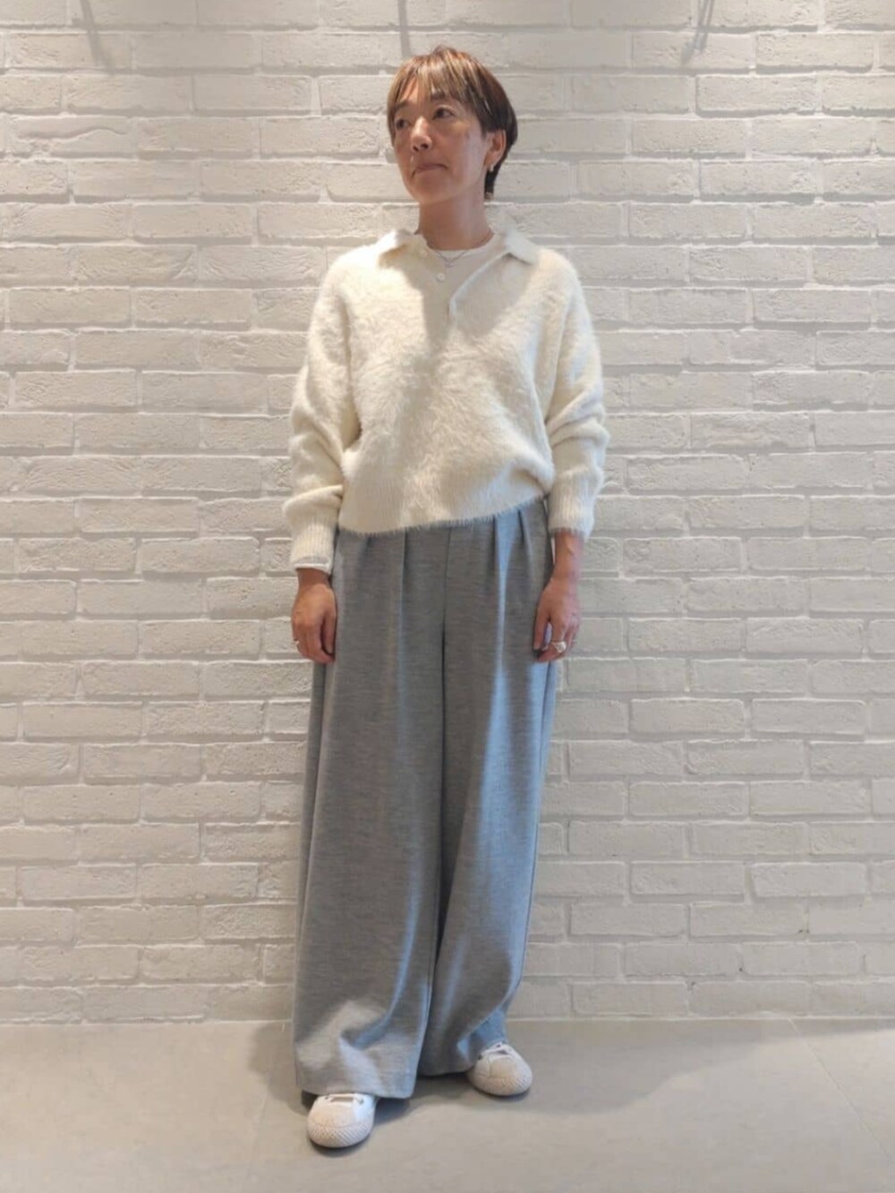 ホワイト系のTシャツ/カットソー、グレー系のその他パンツ、ホワイト系のニット/セーターを着用したレディースの冬コーディネートの2枚目の写真