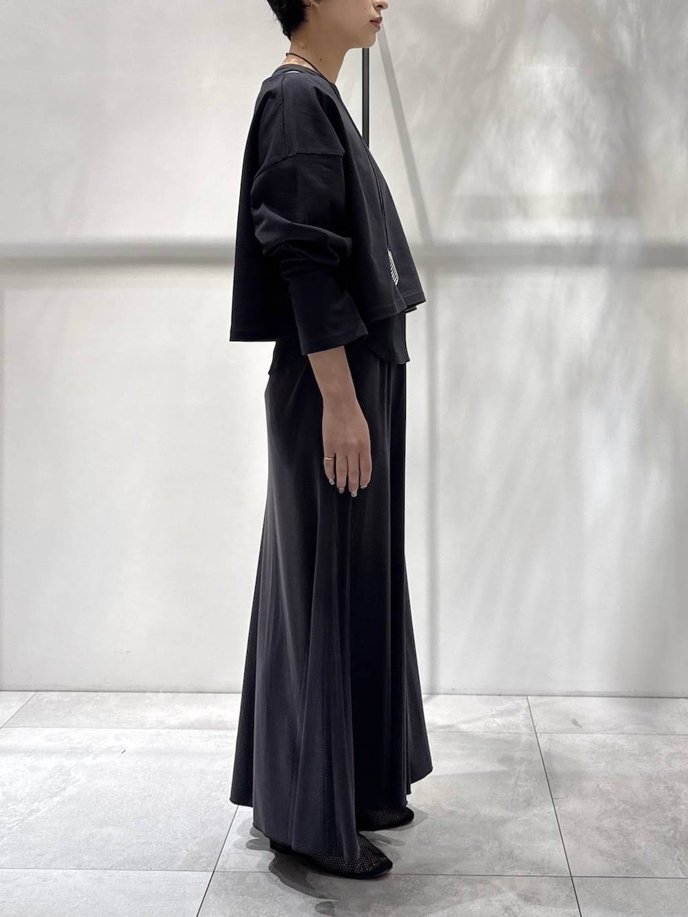 ブラック系のパンプス、グレー系のアンサンブル、グレー系のスカートを着用したレディースの春コーディネートの2枚目の写真