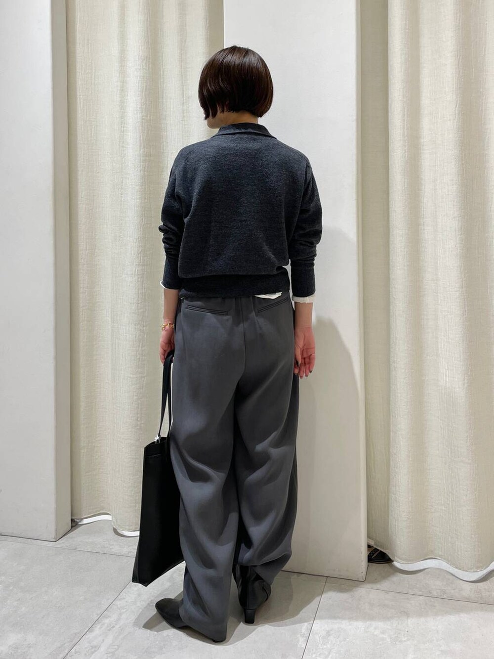 ブラック系のトートバッグ、ホワイト系のTシャツ/カットソー、グレー系のニット/セーターを着用したレディースの秋コーディネートの4枚目の写真