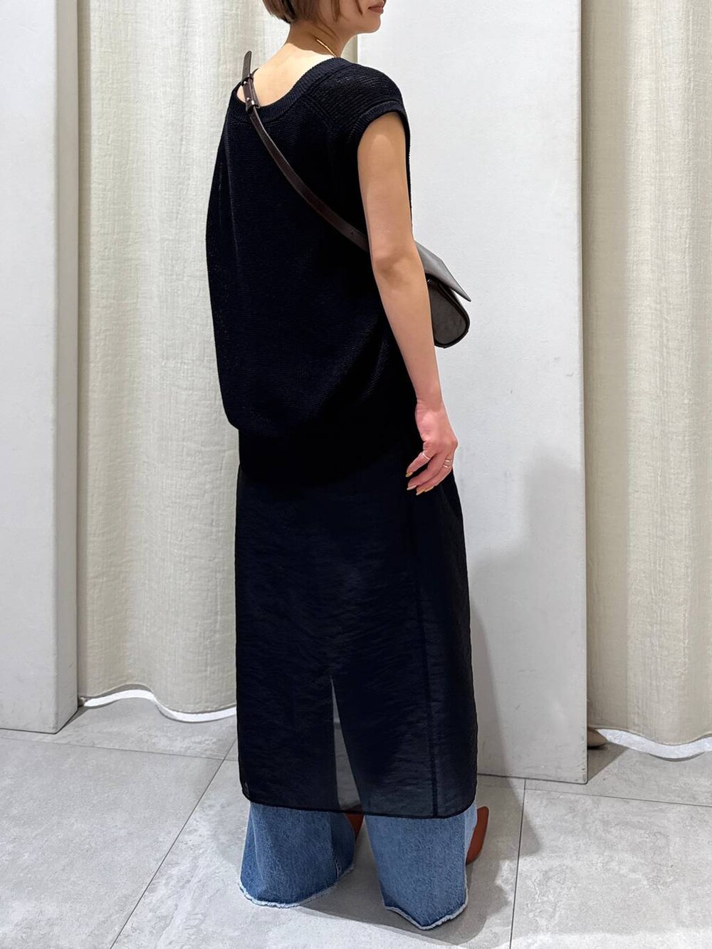 ブラック系のスカート、ブルー系のデニムパンツ、ブラウン系のパンプスを着用したレディースの春コーディネートの3枚目の写真