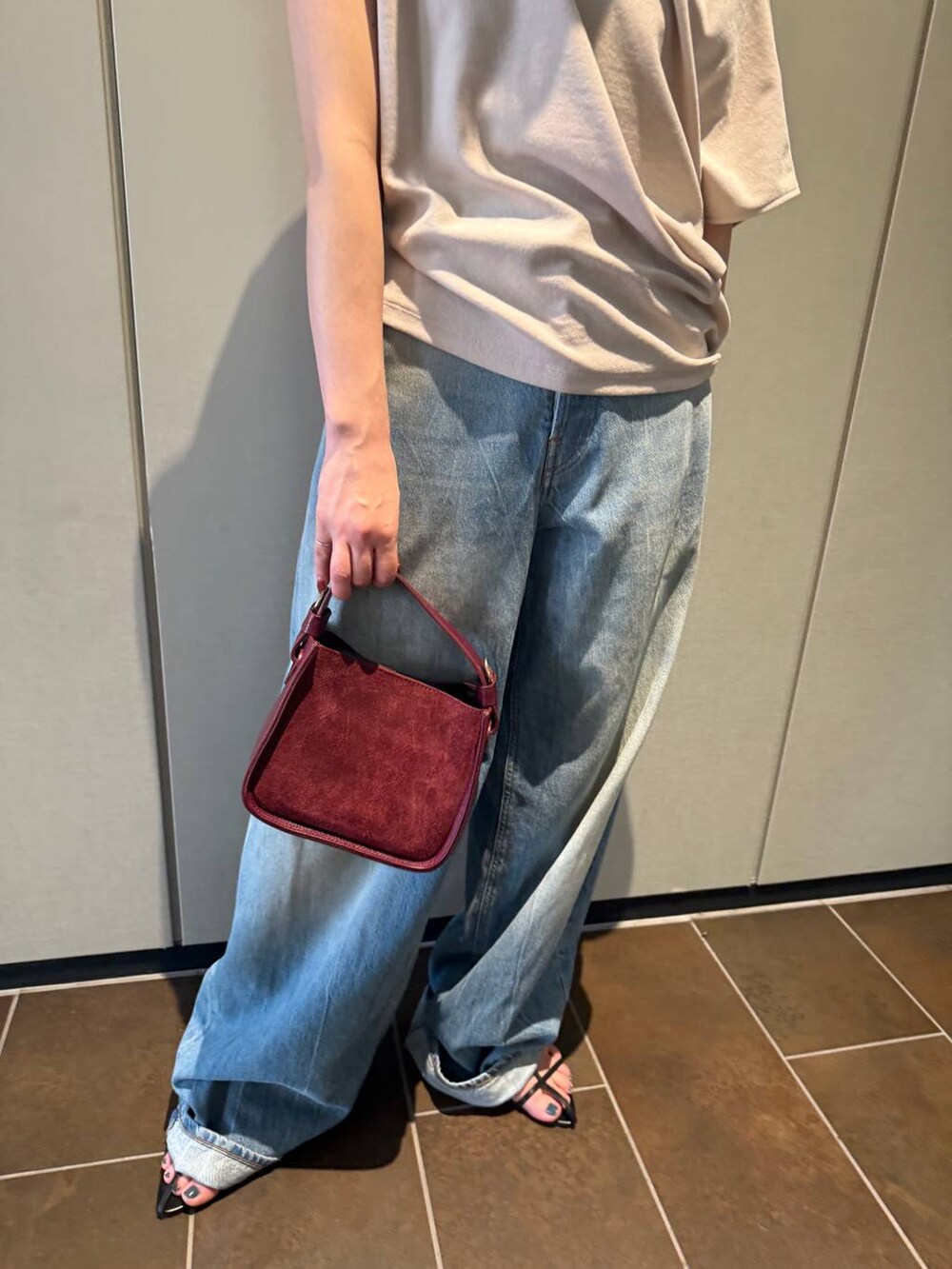 ブラック系のサンダル、ベージュ系のTシャツ/カットソー、ブルー系のデニムパンツを着用したレディースの夏コーディネートの7枚目の写真