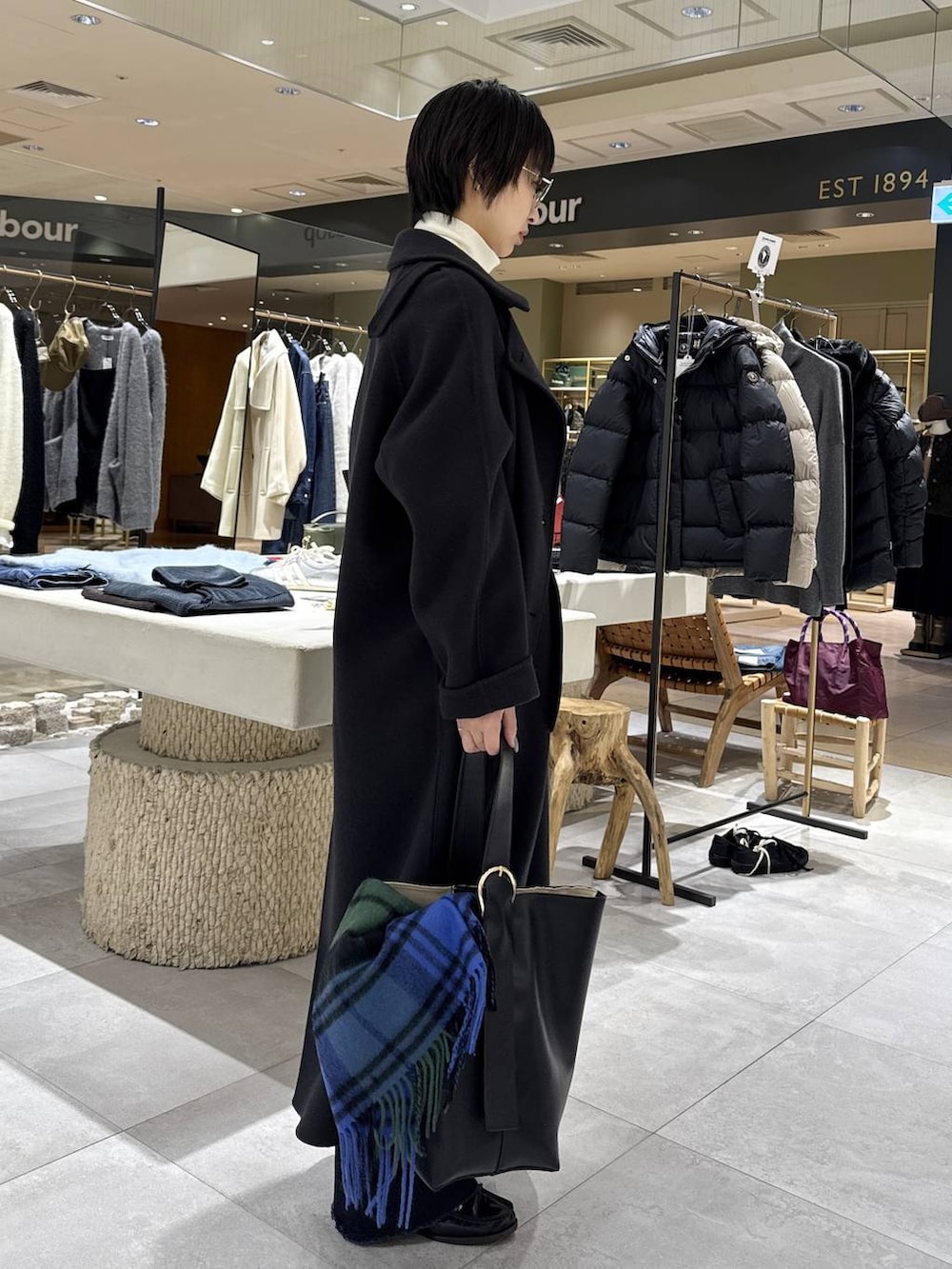 グレー系のステンカラーコート、ホワイト系のニット/セーター、ブラック系のハンドバッグを着用したレディースの秋コーディネートの2枚目の写真