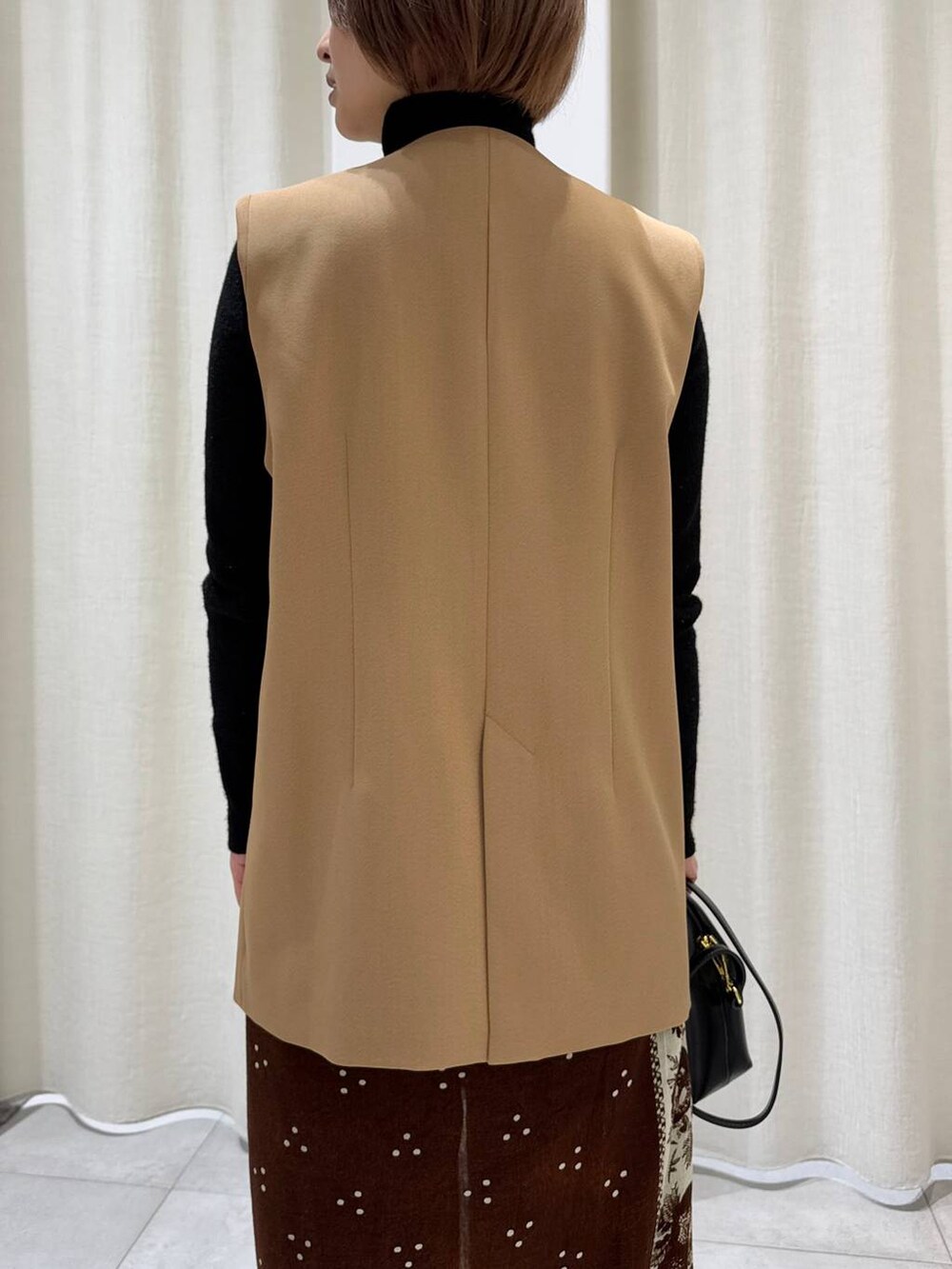 ブラック系のデニムパンツ、ベージュ系のその他アウター、ブラック系のショルダーバッグを着用したレディースの冬コーディネートの6枚目の写真