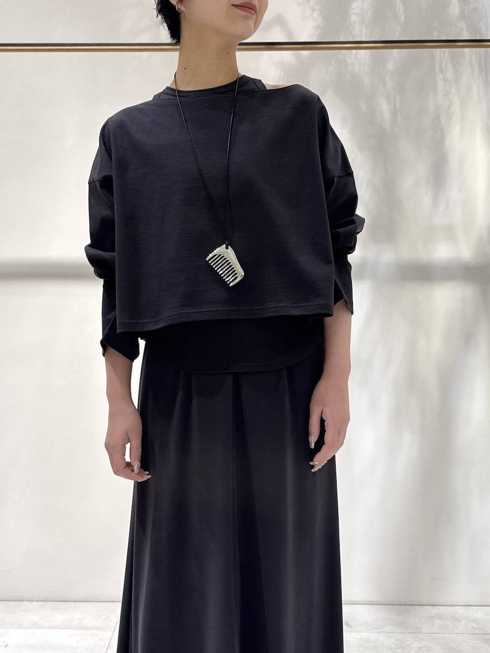 ブラック系のパンプス、グレー系のアンサンブル、グレー系のスカートを着用したレディースの春コーディネートの4枚目の写真