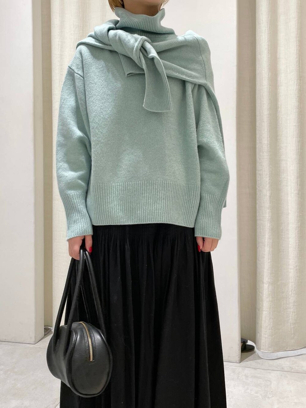 グリーン系のニット/セーター、グリーン系のニット/セーター、ブラック系のスカートを着用したレディースの冬コーディネートの2枚目の写真