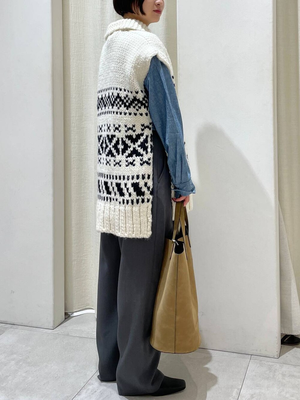 ブラウン系のトートバッグ、ブルー系のシャツ/ブラウス、ホワイト系のベストを着用したレディースの秋コーディネートの4枚目の写真