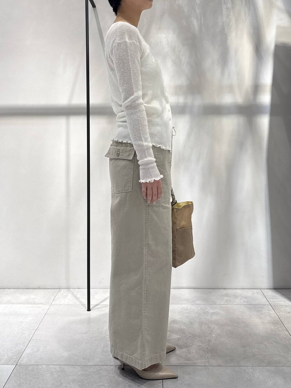 ベージュ系のその他パンツ、ベージュ系のトートバッグ、ホワイト系のカーディガン/ボレロを着用したレディースの冬コーディネートの2枚目の写真