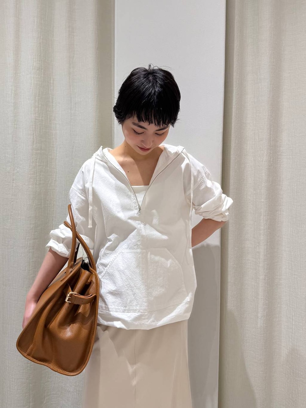 ホワイト系のパーカー、ベージュ系のスカート、ブラウン系のボストンバッグを着用したレディースの冬コーディネートの4枚目の写真