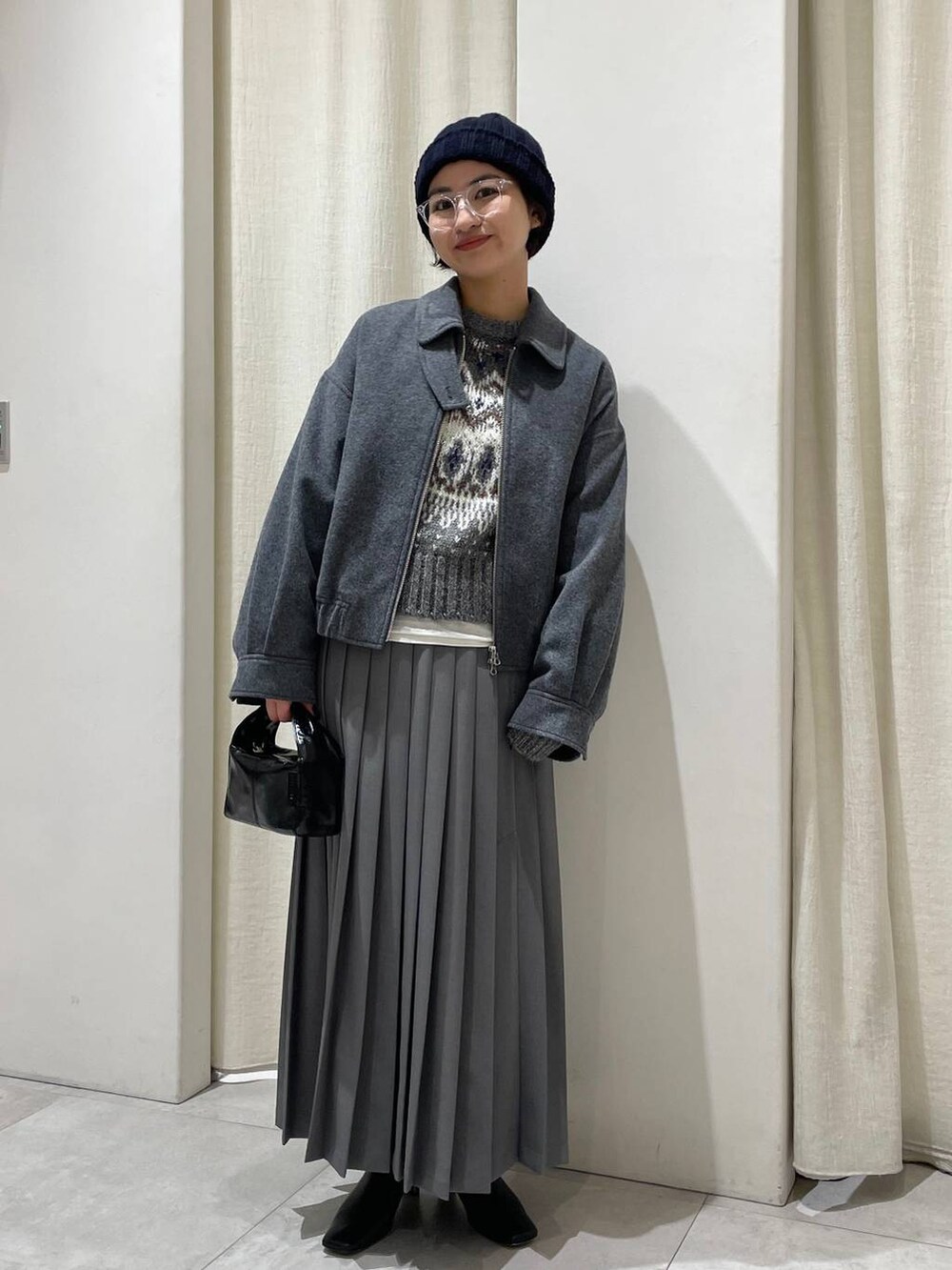 グレー系のニット/セーター、グレー系のスカート、グレー系のブルゾンを着用したレディースの秋コーディネートの2枚目の写真