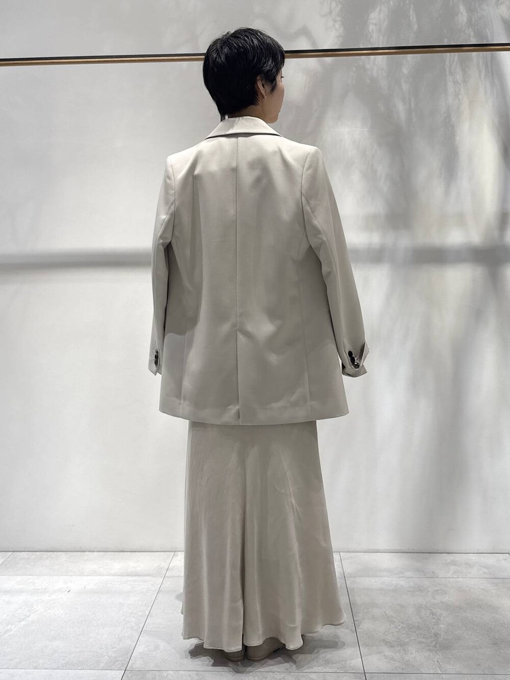 ベージュ系のスカート、ホワイト系のTシャツ/カットソー、ベージュ系のパンプスを着用したレディースの春コーディネートの2枚目の写真