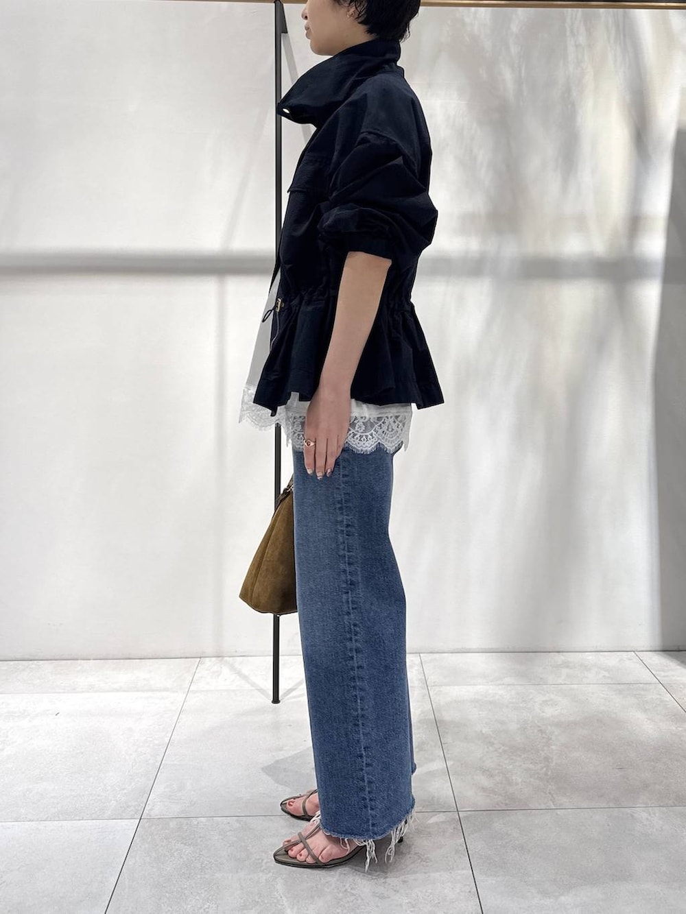 ベージュ系のサンダル、ブラウン系のハンドバッグ、ブルー系のブルゾンを着用したレディースの春コーディネートの2枚目の写真